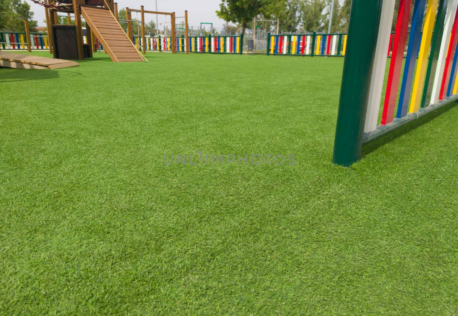Artificial green grass floor on playground. Colourful rows of painted posts arround