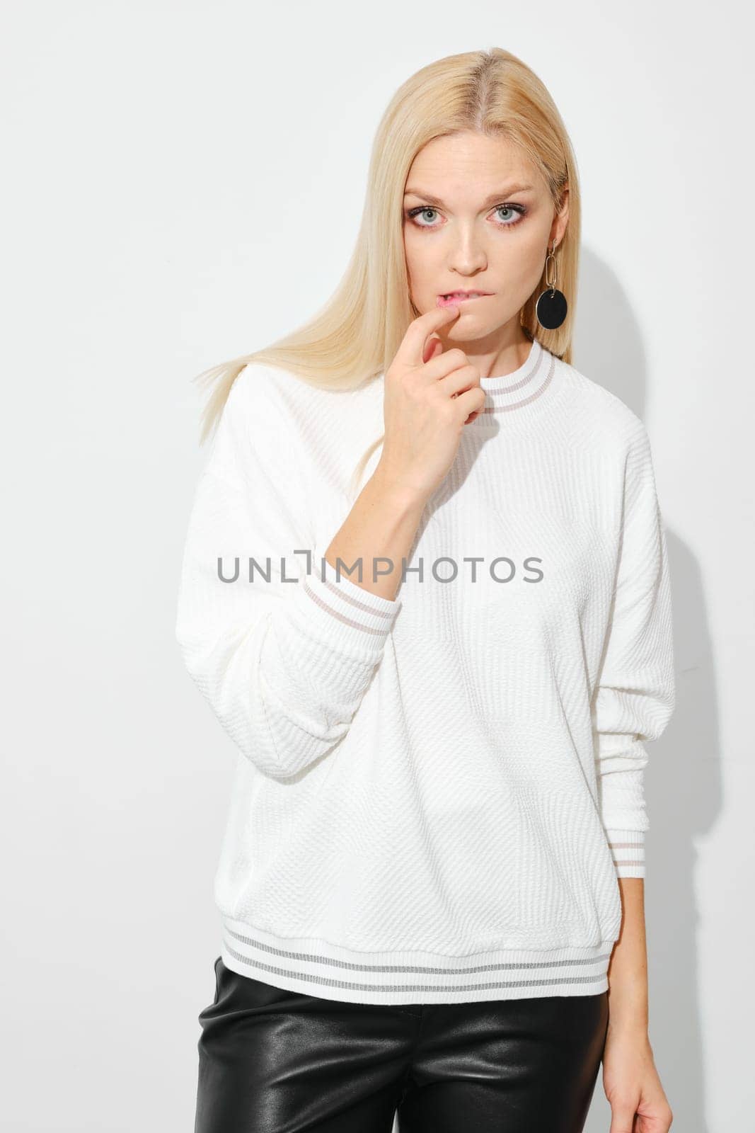 Distrustful or doubting woman biting her lip on white background