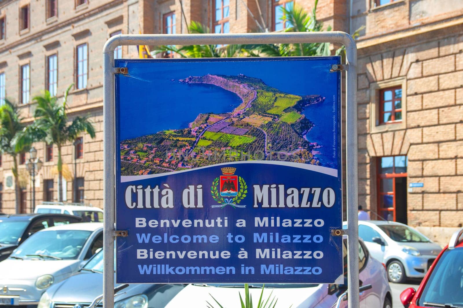 MILAZZO, SICILY, Italy - 03 October 2023. Selective focus on the welcome sign in the centre of Milazzo with an outline map of the town area over blurred city Hall background.