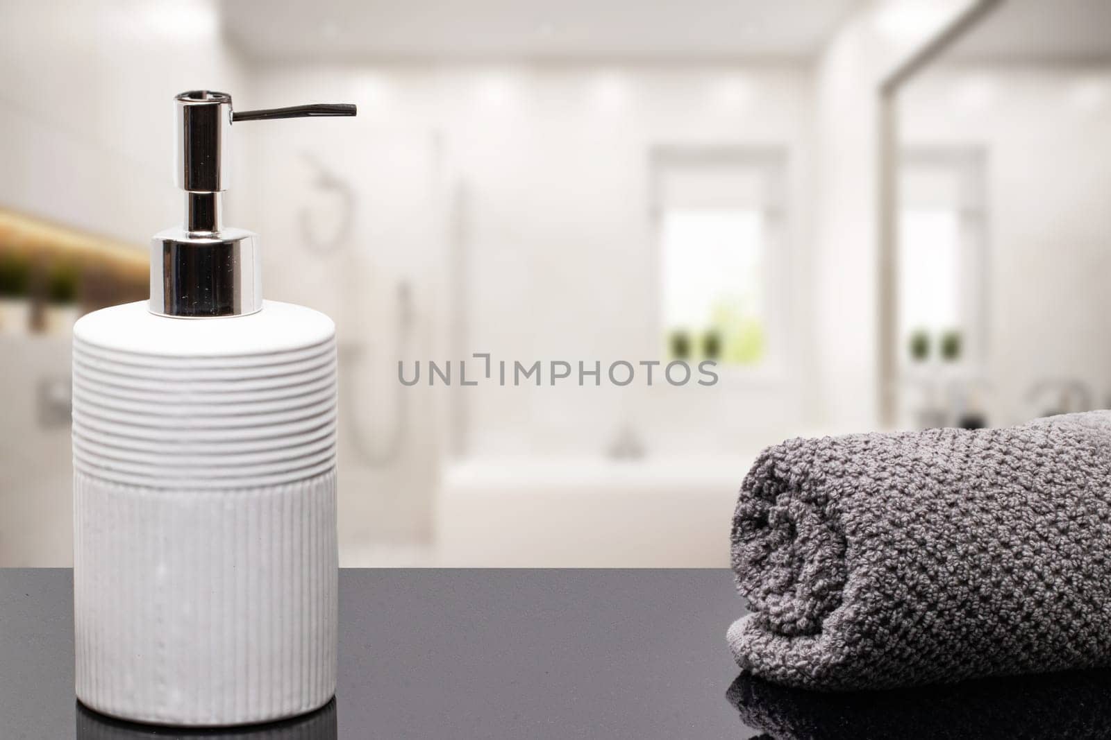 Macro of a beauty cosmetic makeup bottle and a fresh soft terry bath towel on dark table table over blurred bathroom background. Space. Beauty and Wellness concept.