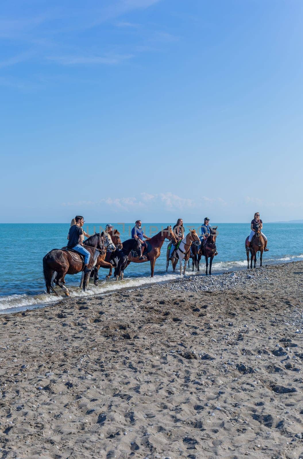 Policoro, Italy - 7 May 2023: People riding horses in a Policoro beach, Basilicata, southern Italy.