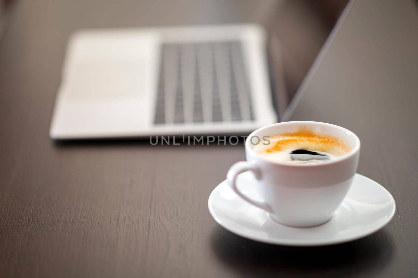 cup of coffee and laptop on wooden table