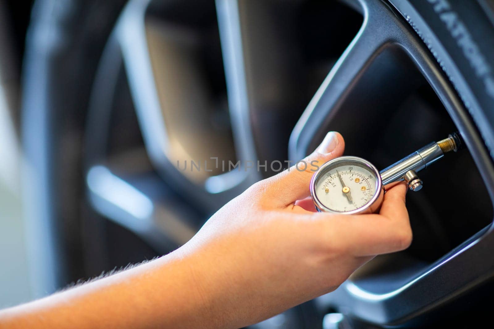 Hand holding pressure gauge for car tire