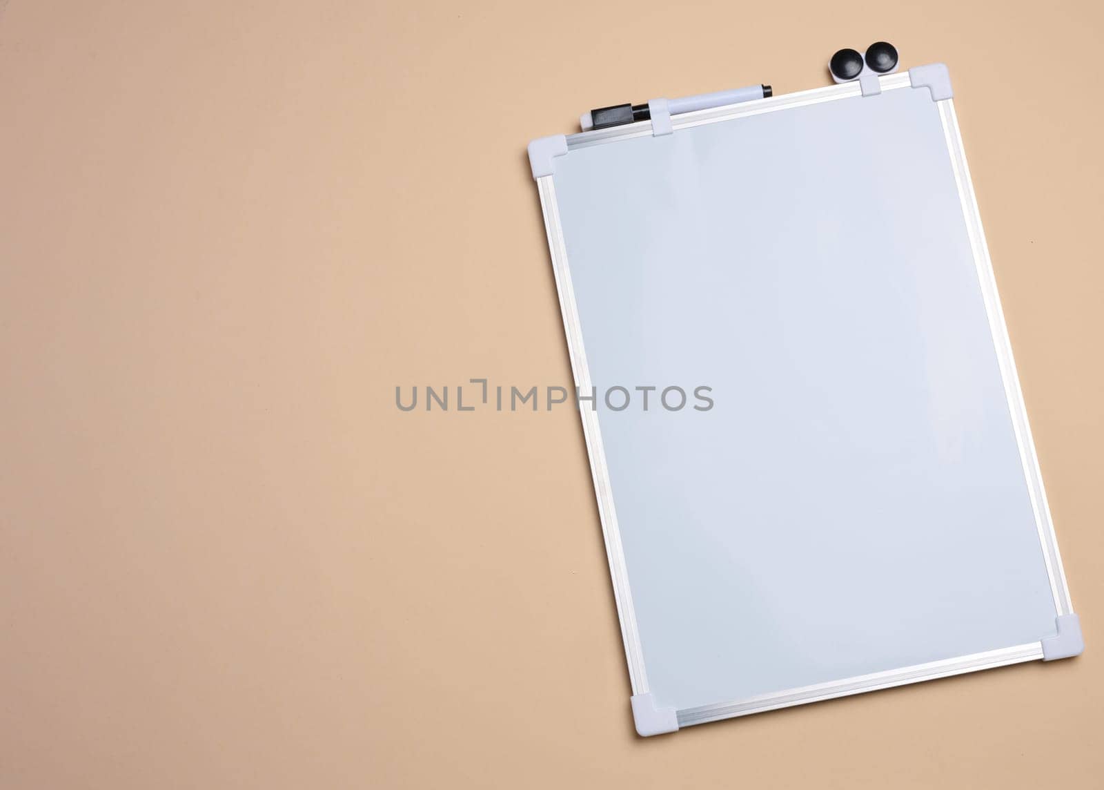 Empty white board for markers on beige background. Copy space