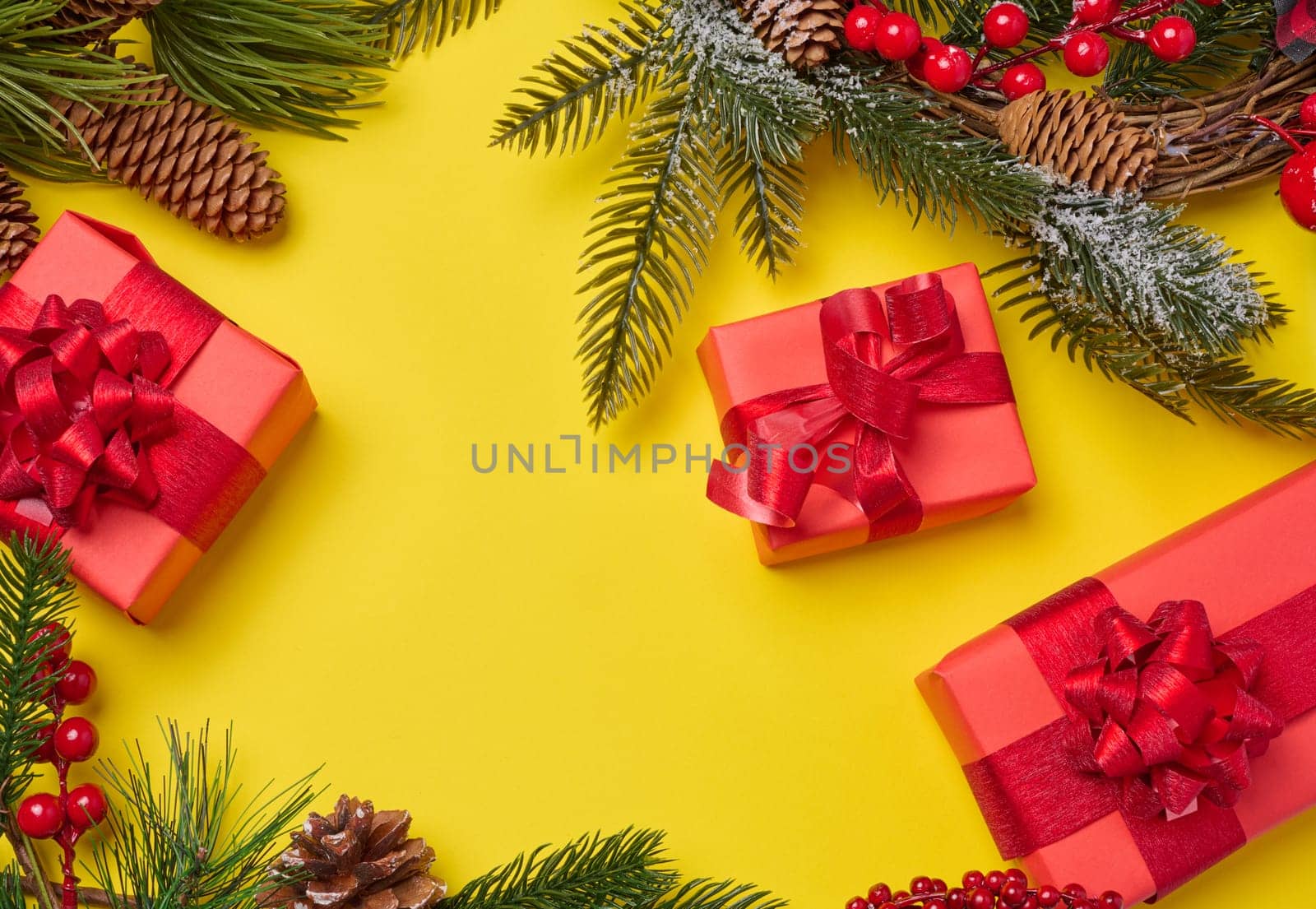 Christmas decor, gifts wrapped in red paper on a yellow background, top view. Copy space