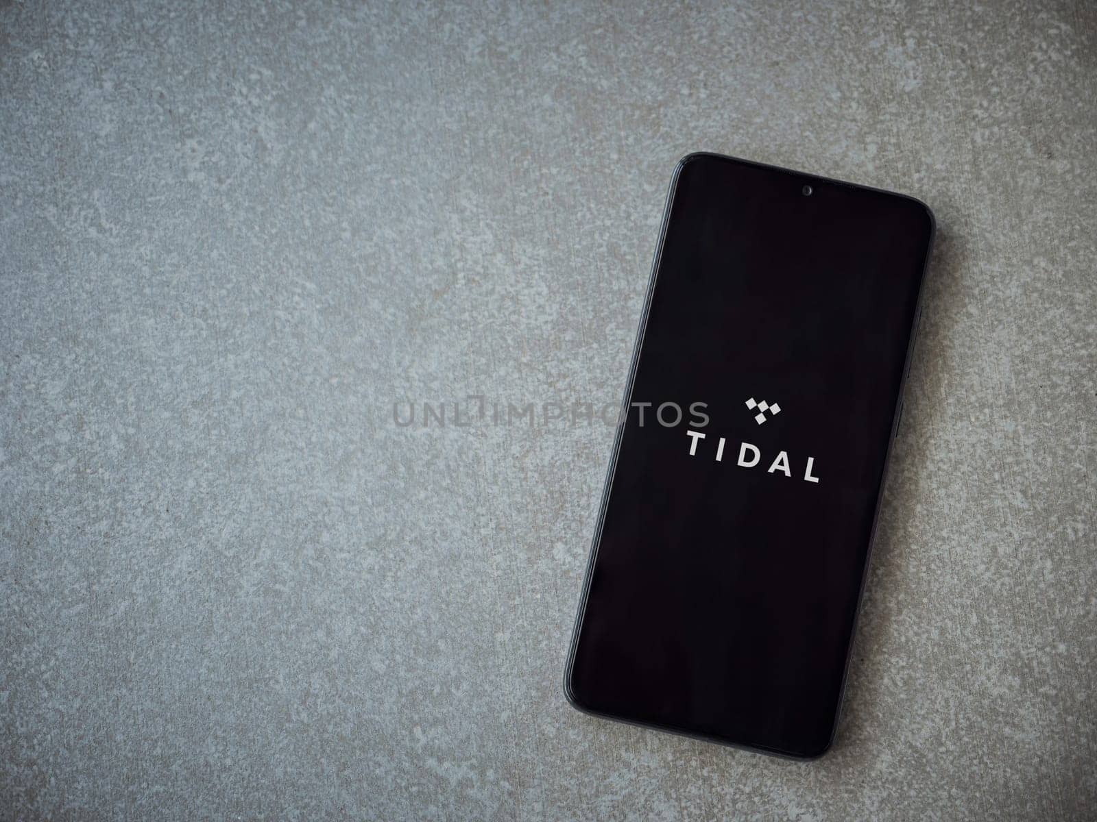 Lod, Israel - July 16,2023: TIDAL Music app launch screen on smartphone on ceramic stone background. Top view flat lay with copy space.