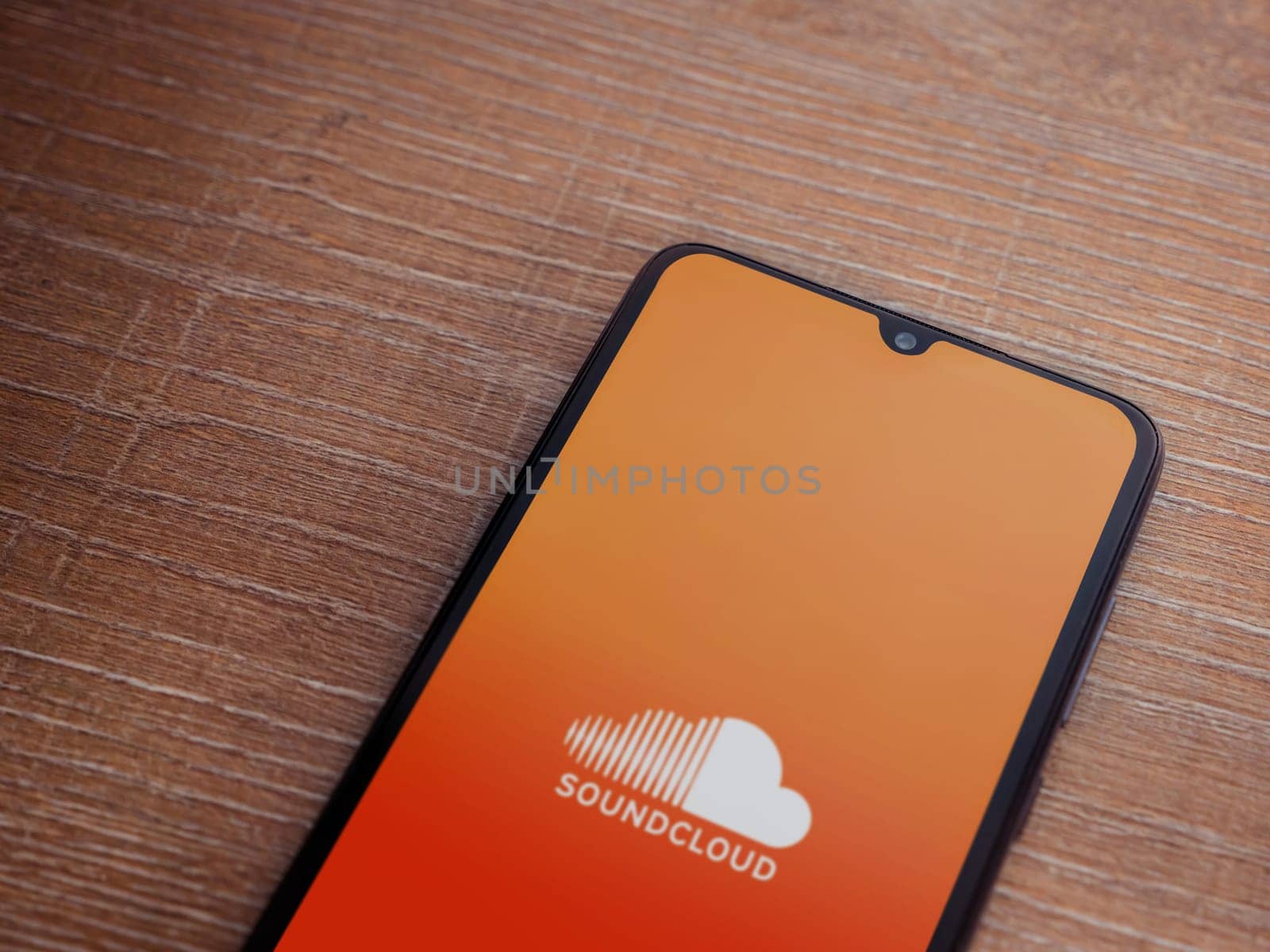Lod, Israel - July 16,2023: SoundCloud app launch screen on smartphone on wooden background. Top view flat lay with copy space.