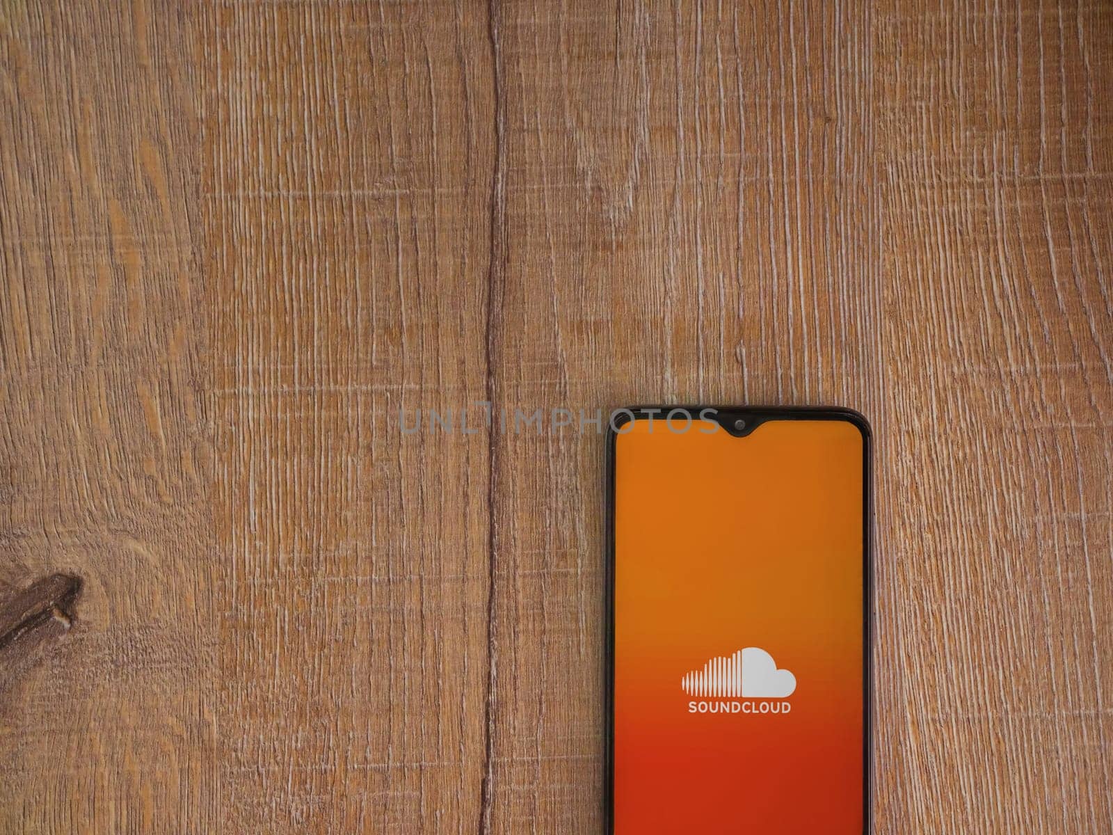 Lod, Israel - July 16,2023: SoundCloud app launch screen on smartphone on wooden background. Top view flat lay with copy space.