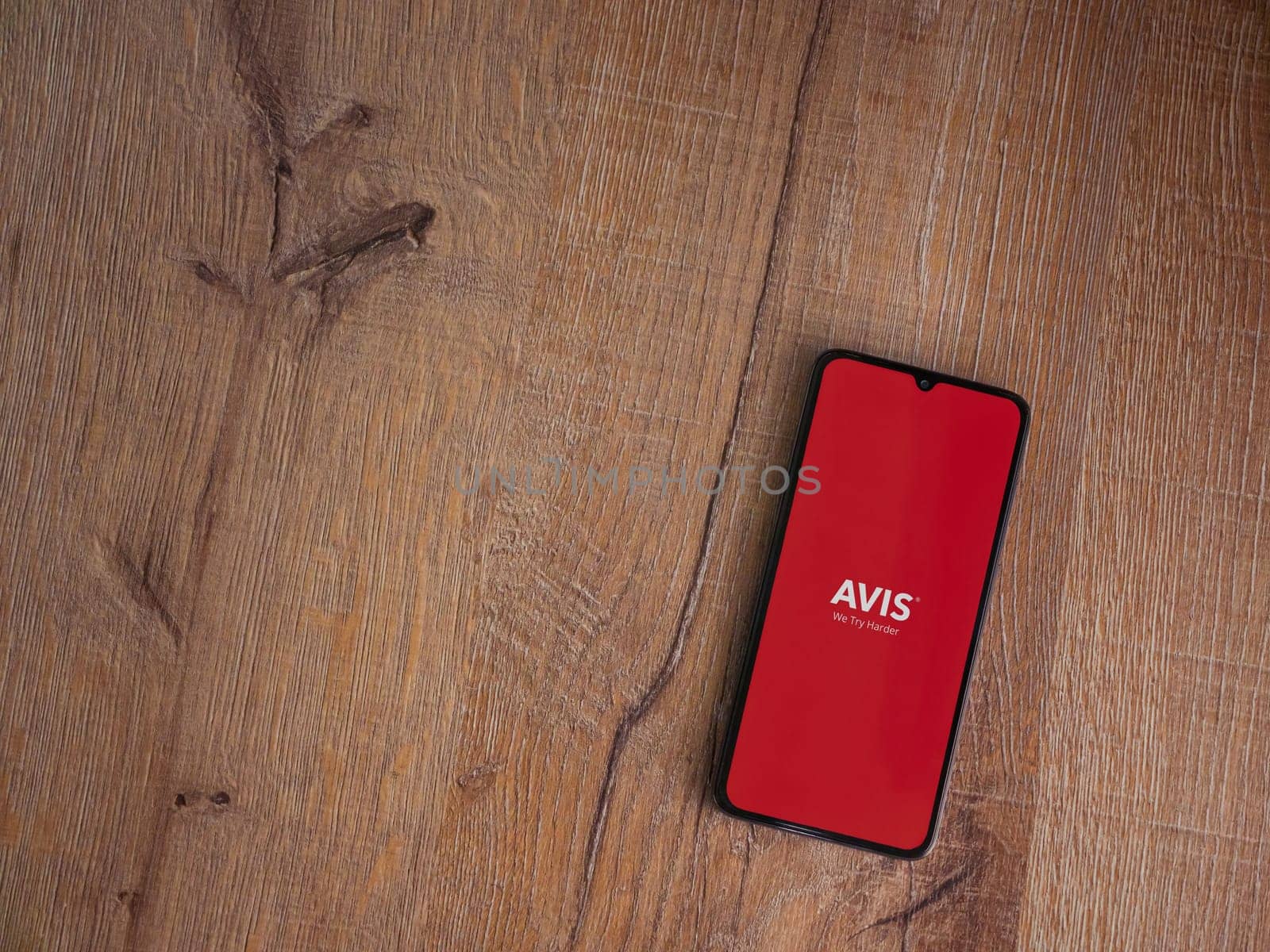 Lod, Israel - July 16,2023: Avis IL app launch screen on smartphone on wooden background. Top view flat lay with copy space.