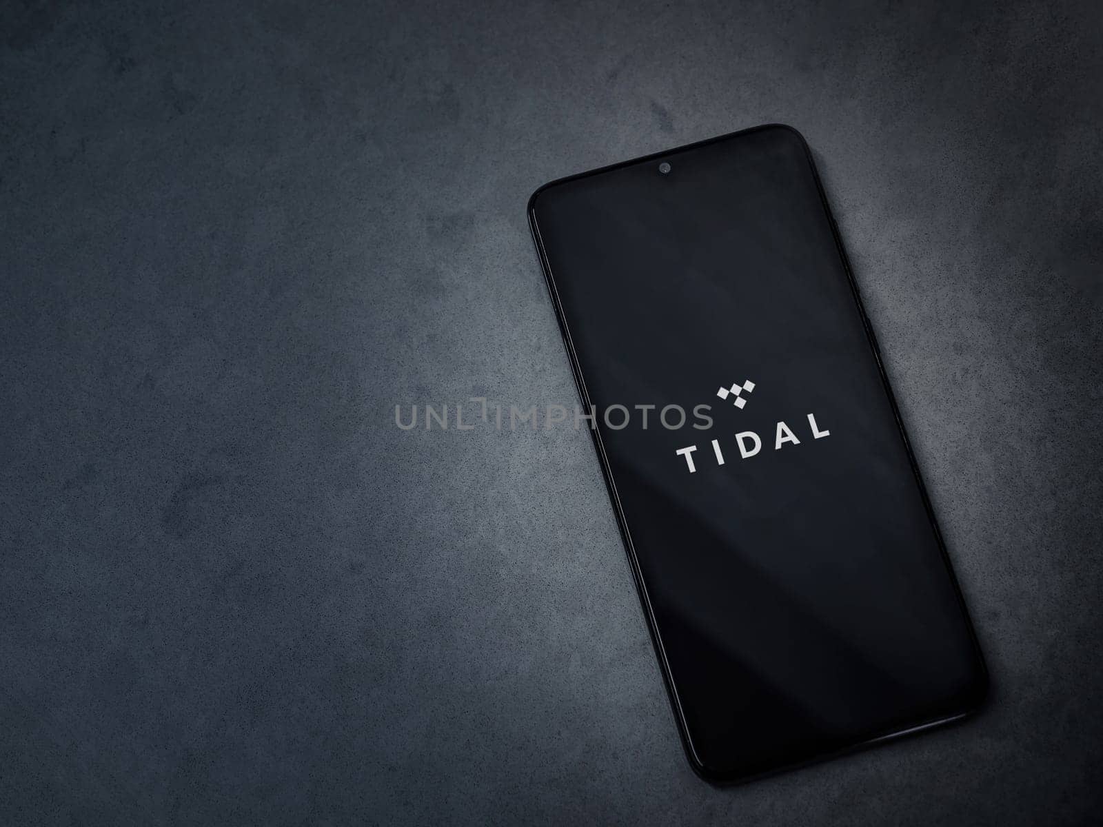 Lod, Israel - July 16,2023: TIDAL Music app launch screen on smartphone on dark marble stone background. Top view flat lay with copy space.