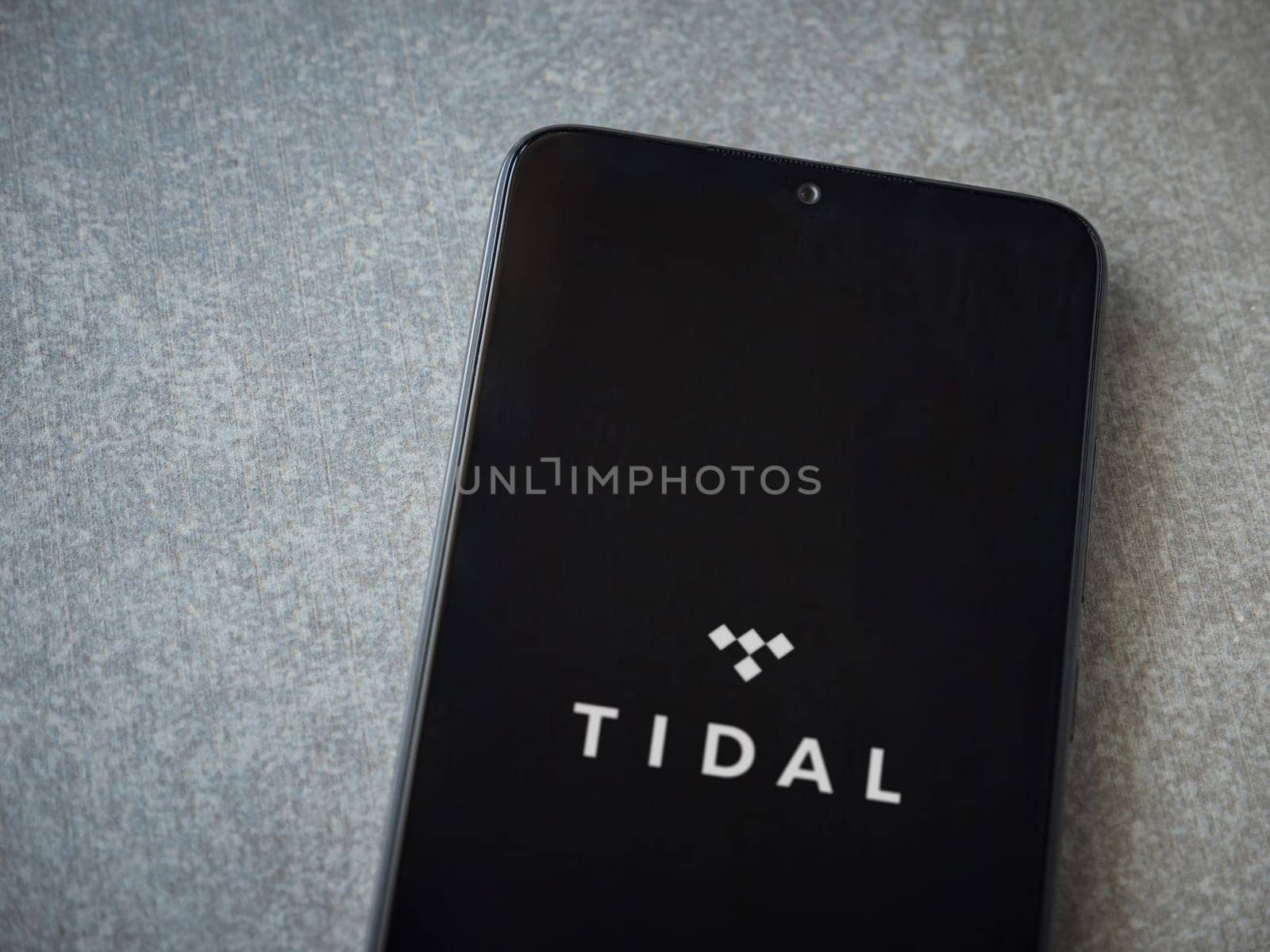 Lod, Israel - July 16,2023: TIDAL Music app launch screen on smartphone on ceramic stone background. Top view flat lay with copy space.