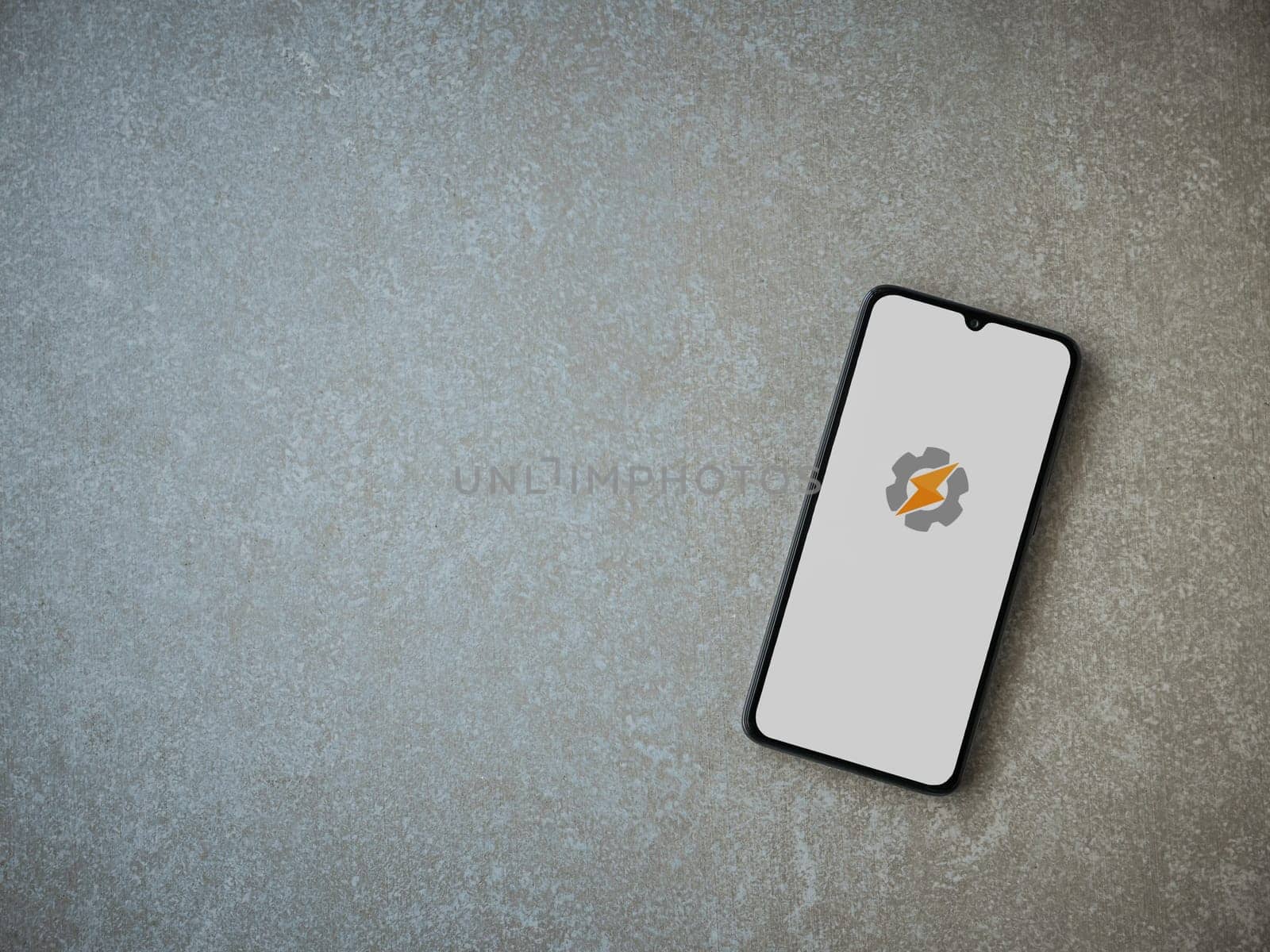 Lod, Israel - July 16,2023: Tasker app launch screen on smartphone on ceramic stone background. Top view flat lay with copy space.