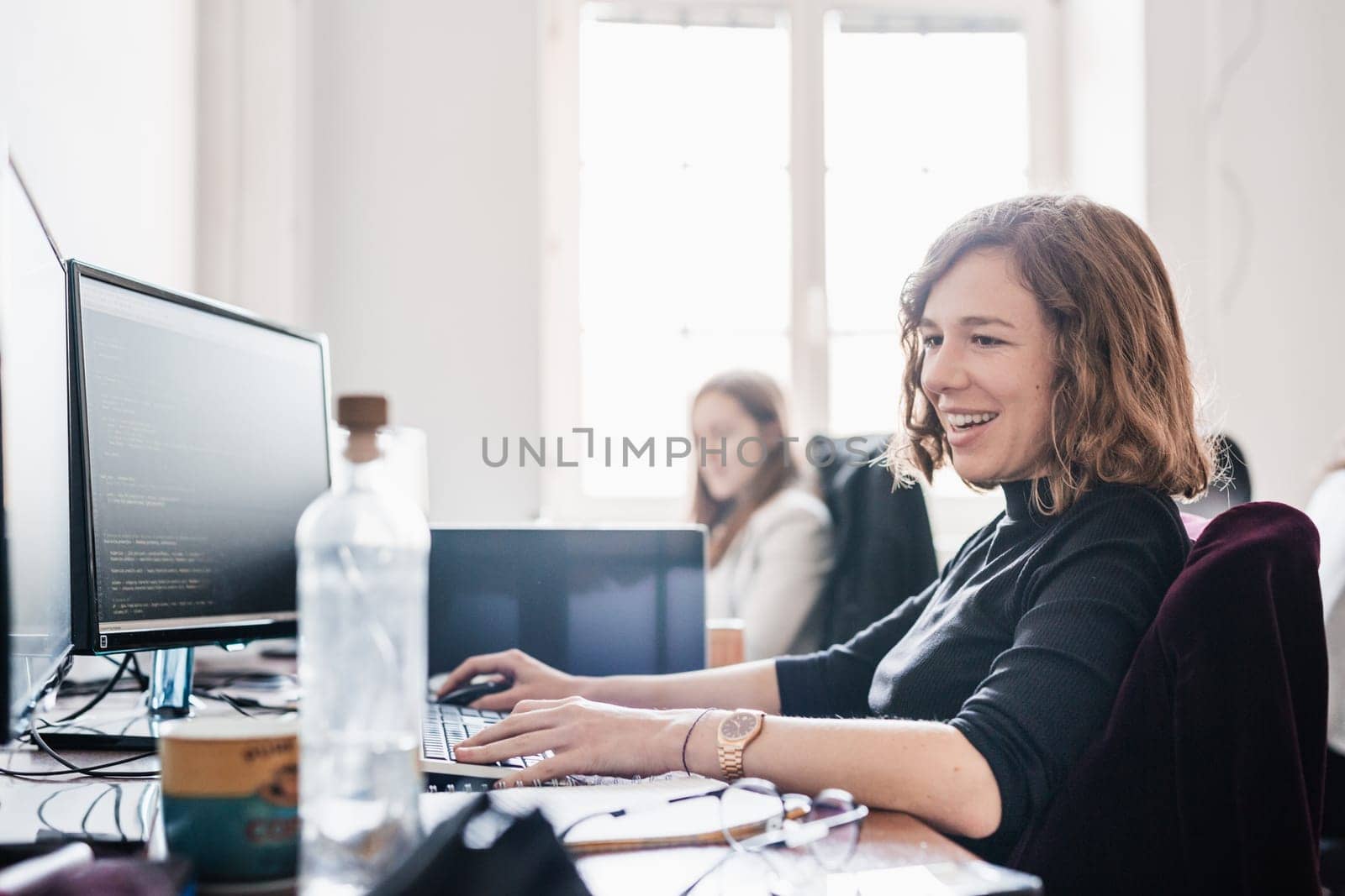 Women in startup business and entrepreneurship. Yound devoted female AI programmers and IT software developers team programming on desktop computer in startup company share office space.