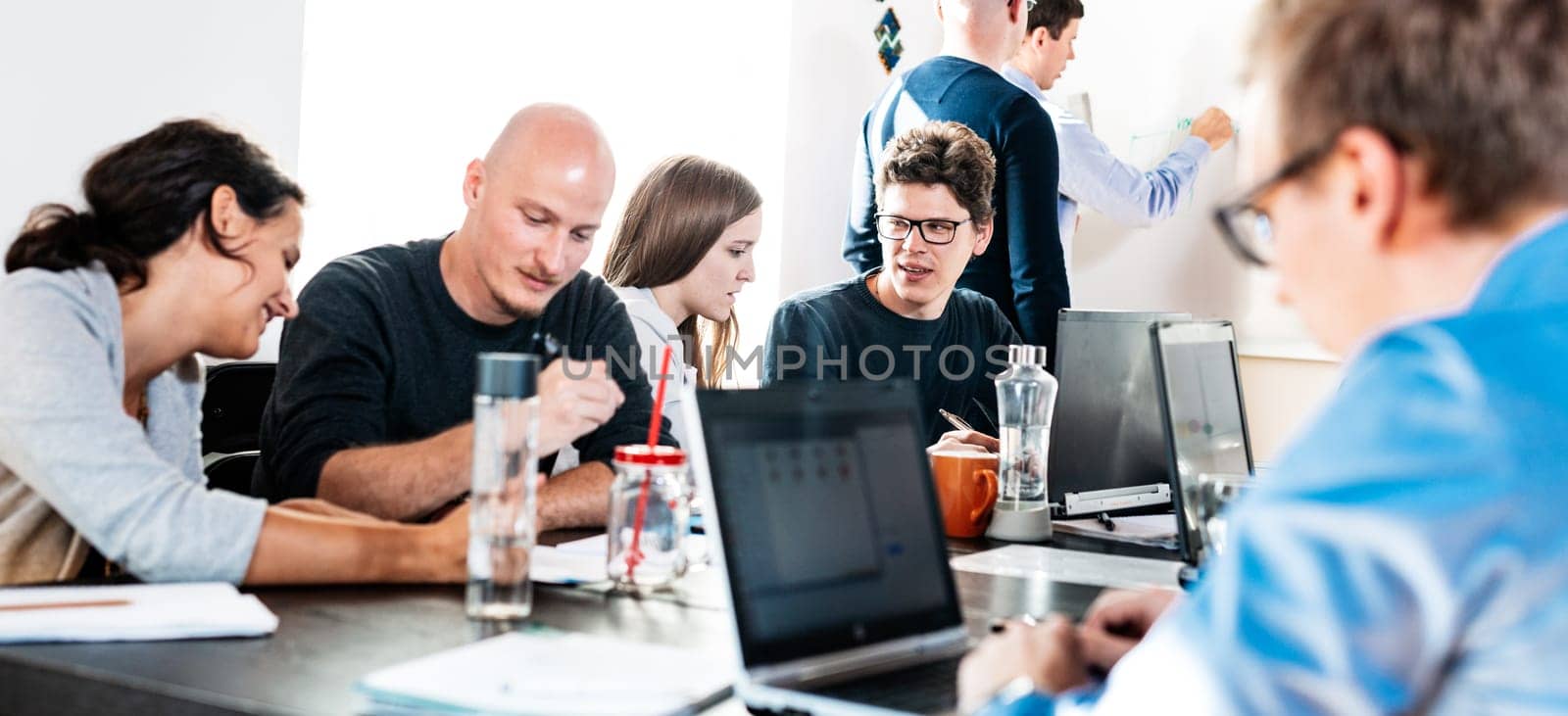 Startup business and entrepreneurship problem solving. Young AI programmers and IT software developers team brainstorming and programming on desktop computer in startup company share office space