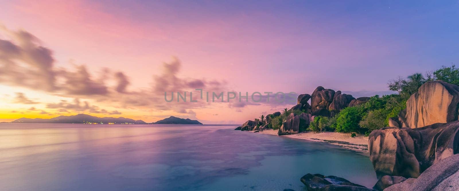 Beautifully shaped granite boulders and a dramatic sunset at picture perfect tropical Anse Source d'Argent beach, La Digue island, Seychelles.