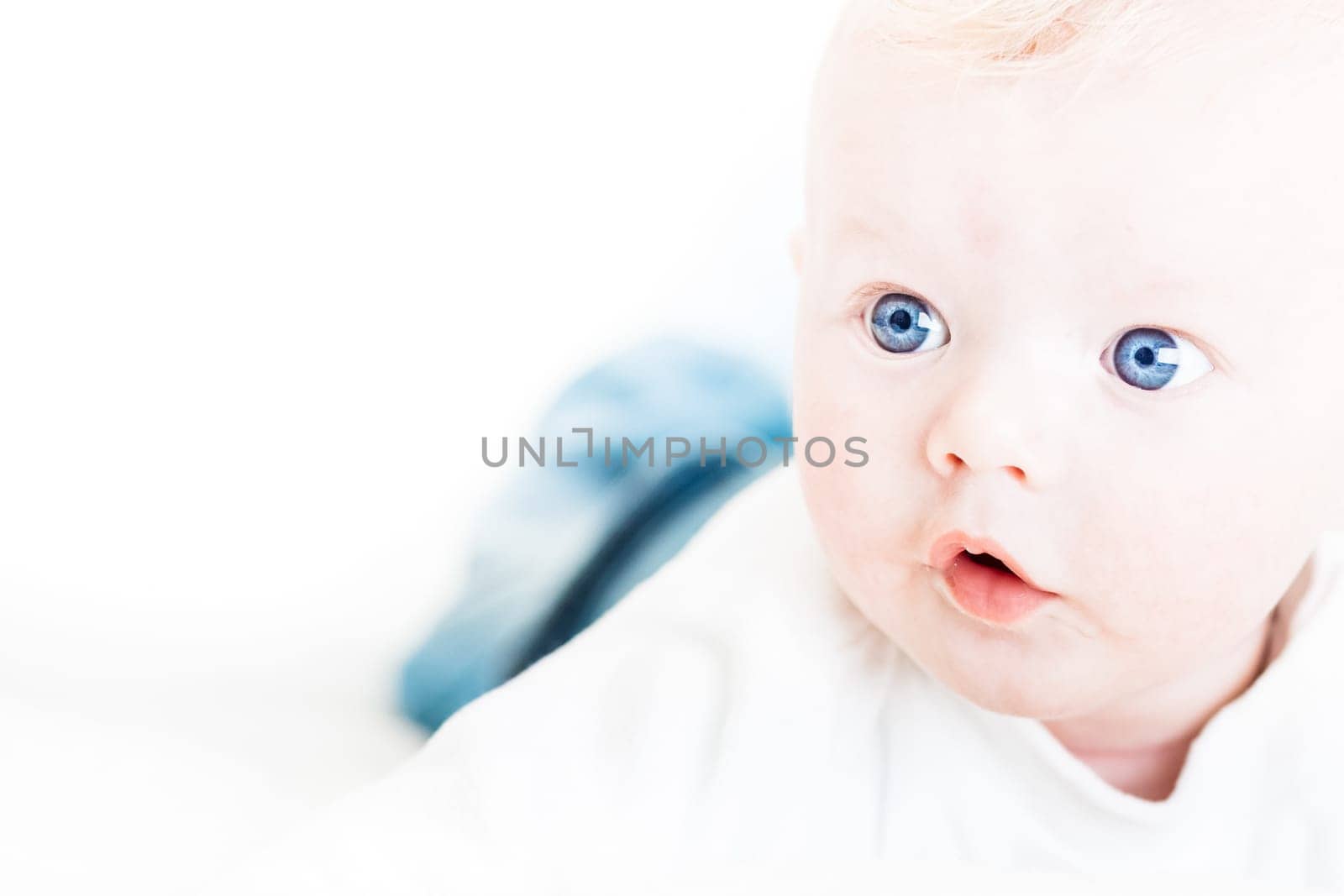 Cute blonde little baby boy with blue eyes. Copy space on left.