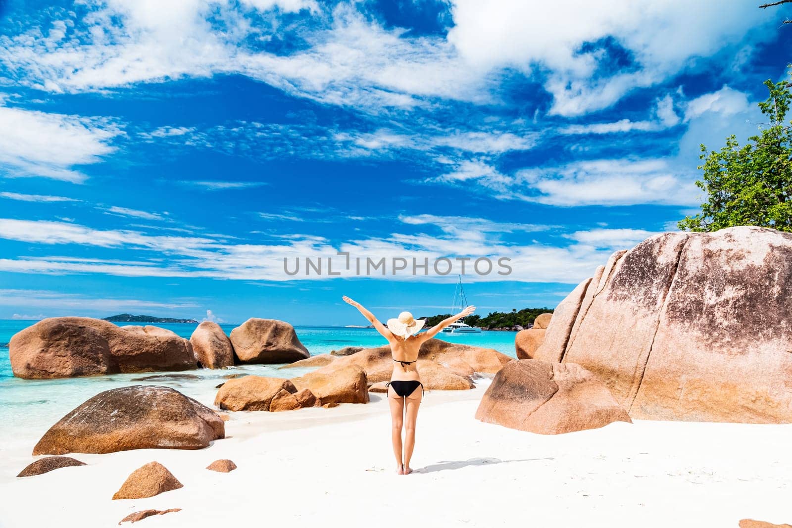 Happy woman rising hands to the sky on summer vacations on Seychelles.