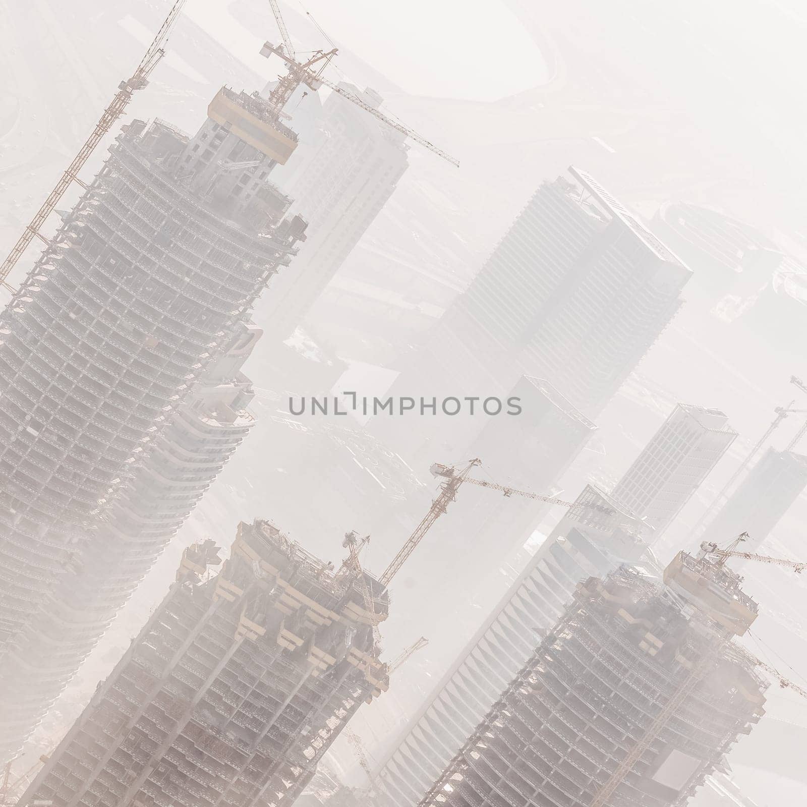 Huge skyscrappers construction site with cranes on top of buildings. Rapid urban and construction sector development or inflation of real estate bubble.