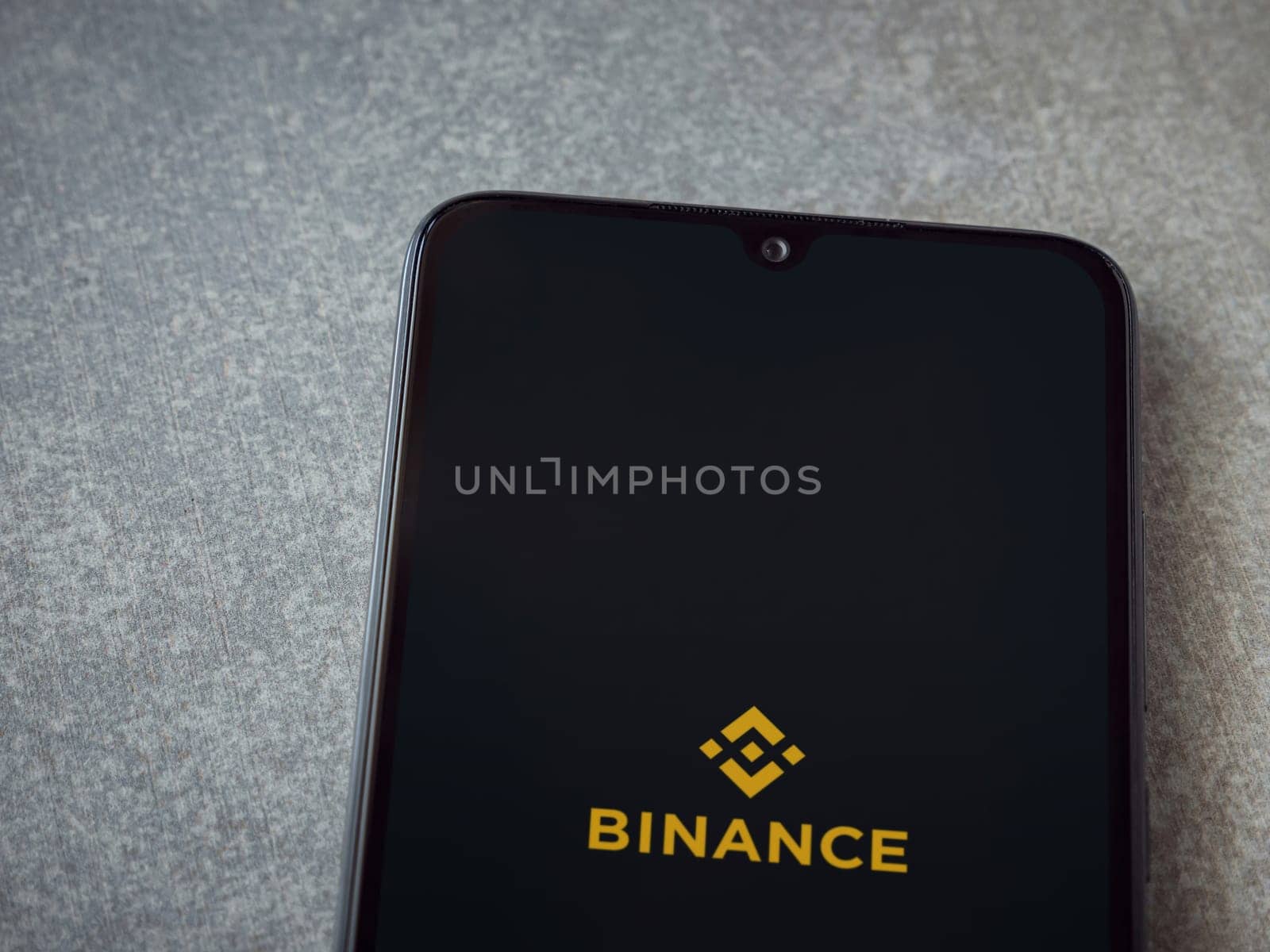 Lod, Israel - July 16,2023: Binance app launch screen on smartphone on ceramic stone background. Top view flat lay with copy space.