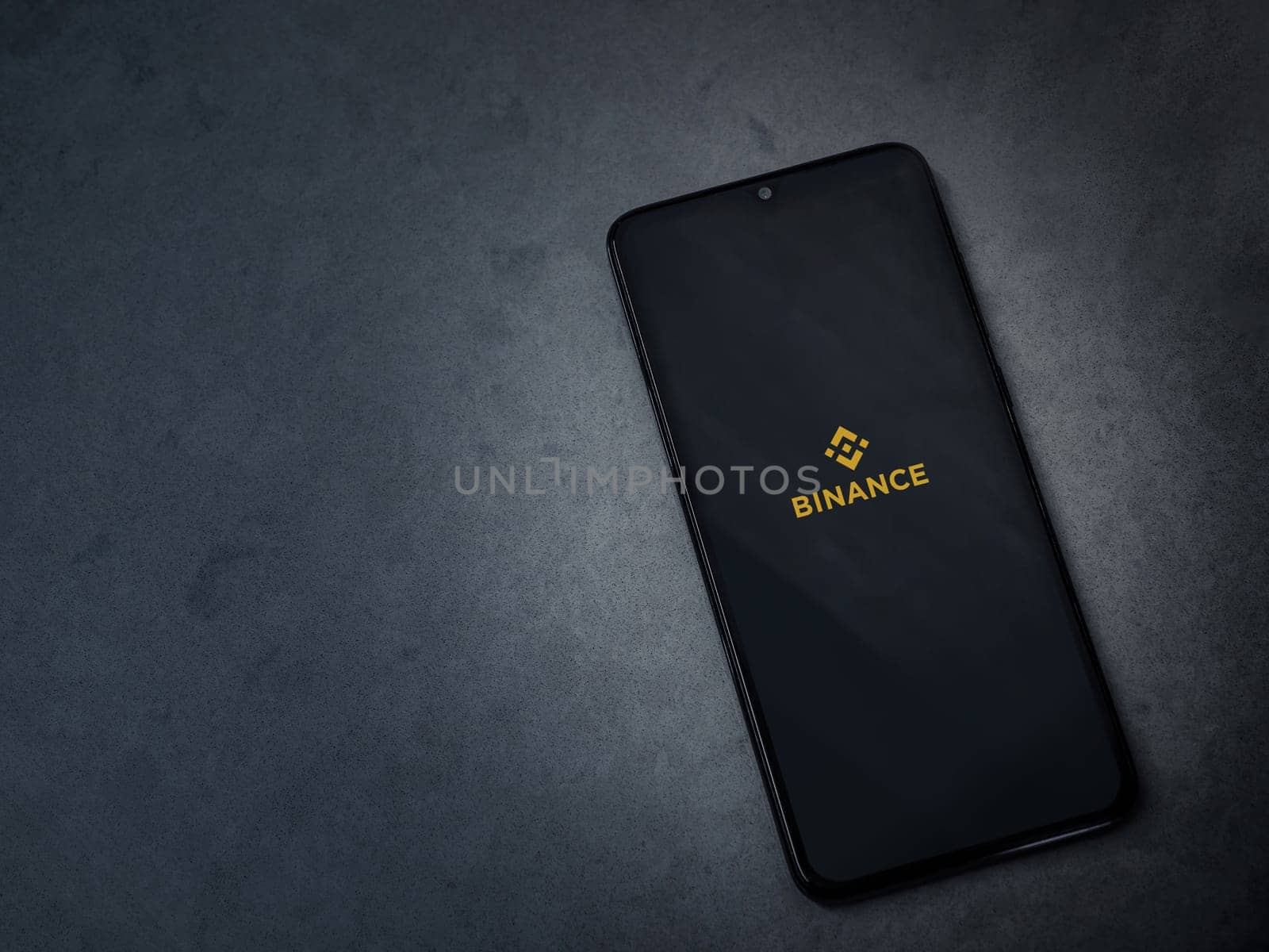 Lod, Israel - July 16,2023: Binance app launch screen on smartphone on dark marble stone background. Top view flat lay with copy space.