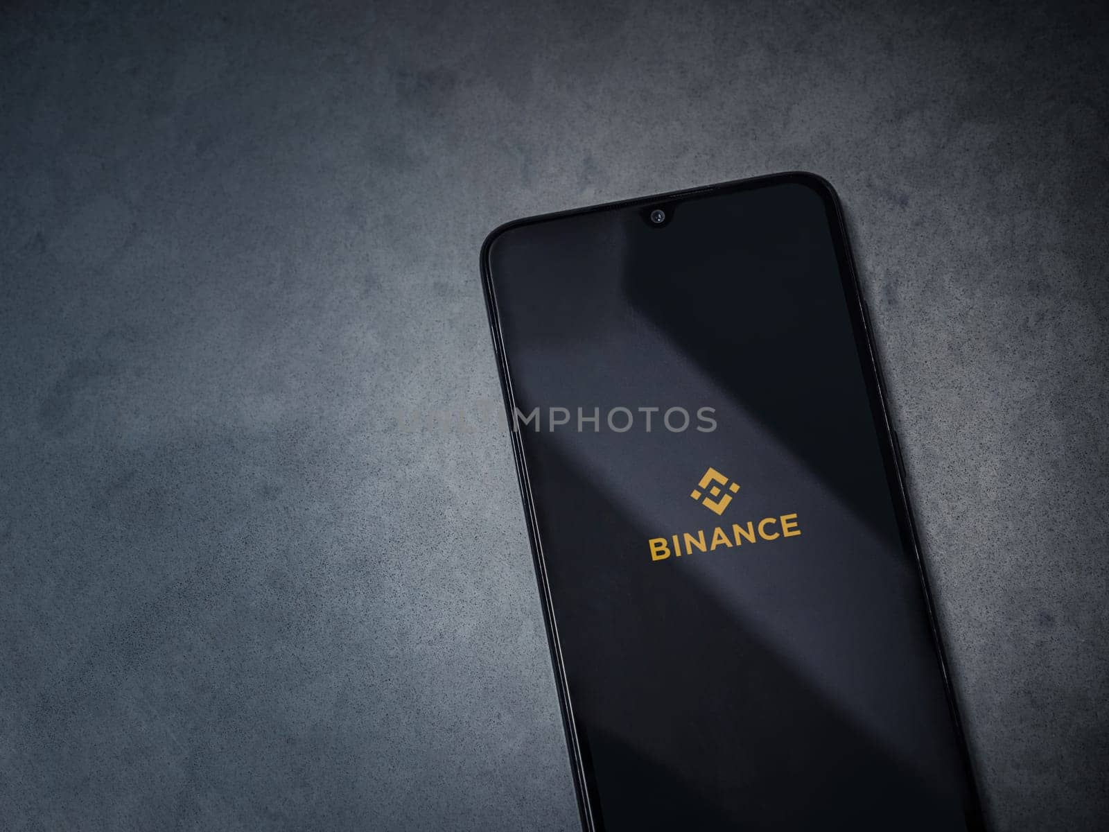 Lod, Israel - July 16,2023: Binance app launch screen on smartphone on dark marble stone background. Top view flat lay with copy space.