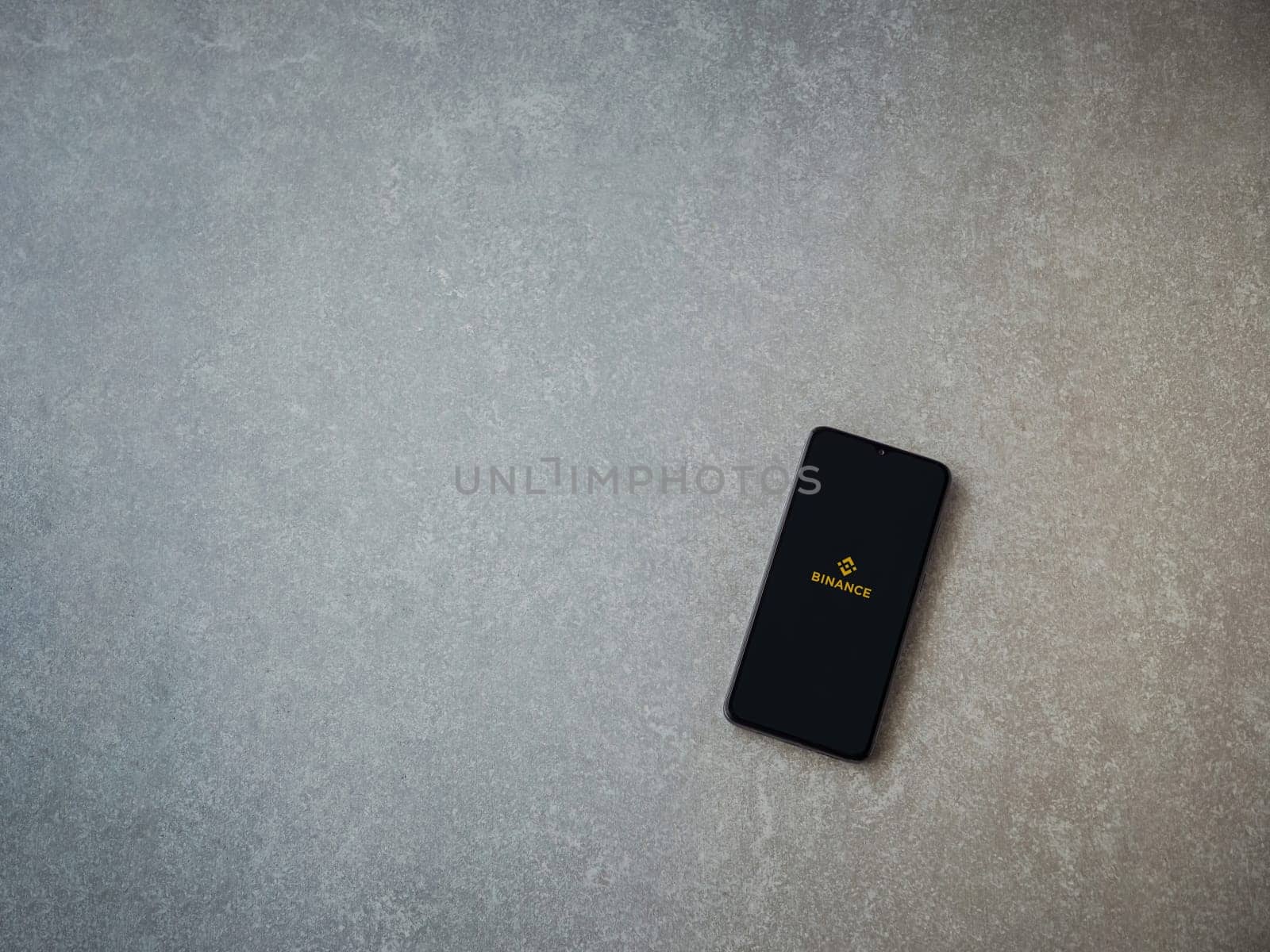 Lod, Israel - July 16,2023: Binance app launch screen on smartphone on ceramic stone background. Top view flat lay with copy space.