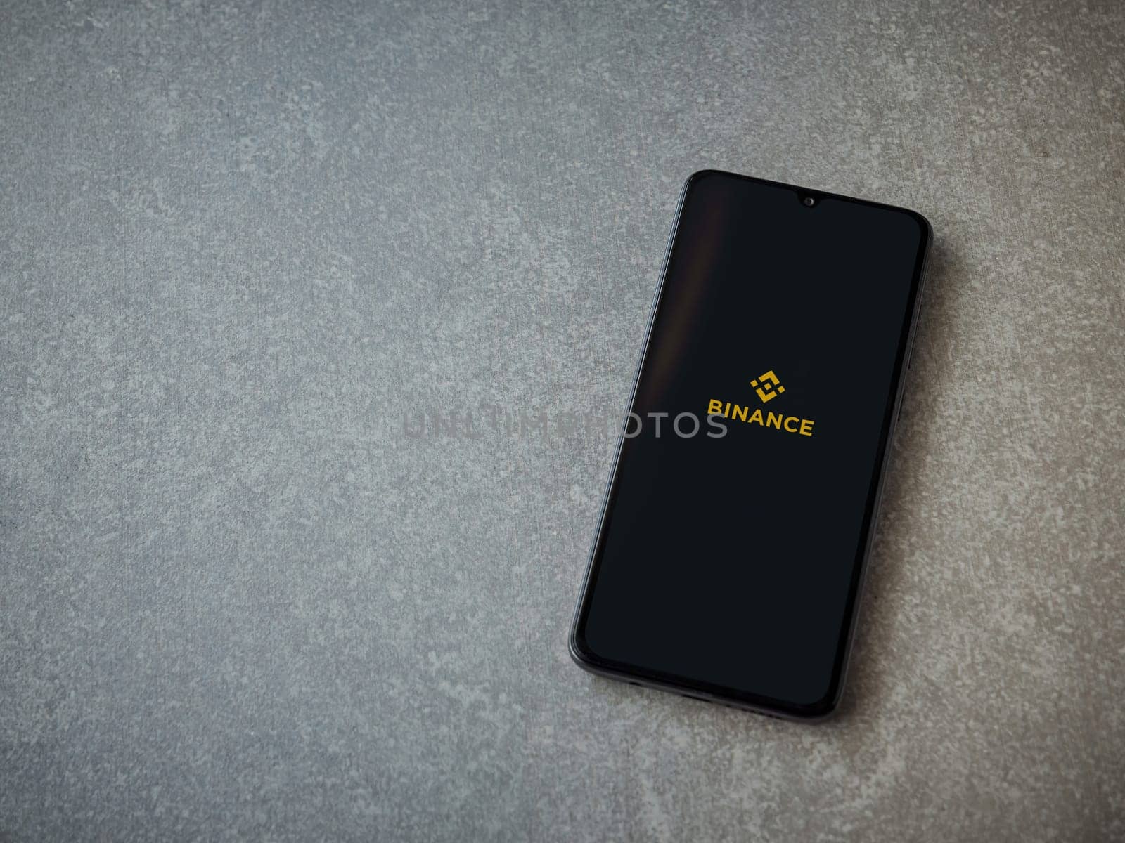 Lod, Israel - July 16,2023: Binance app launch screen on smartphone on ceramic stone background. Top view flat lay with copy space.