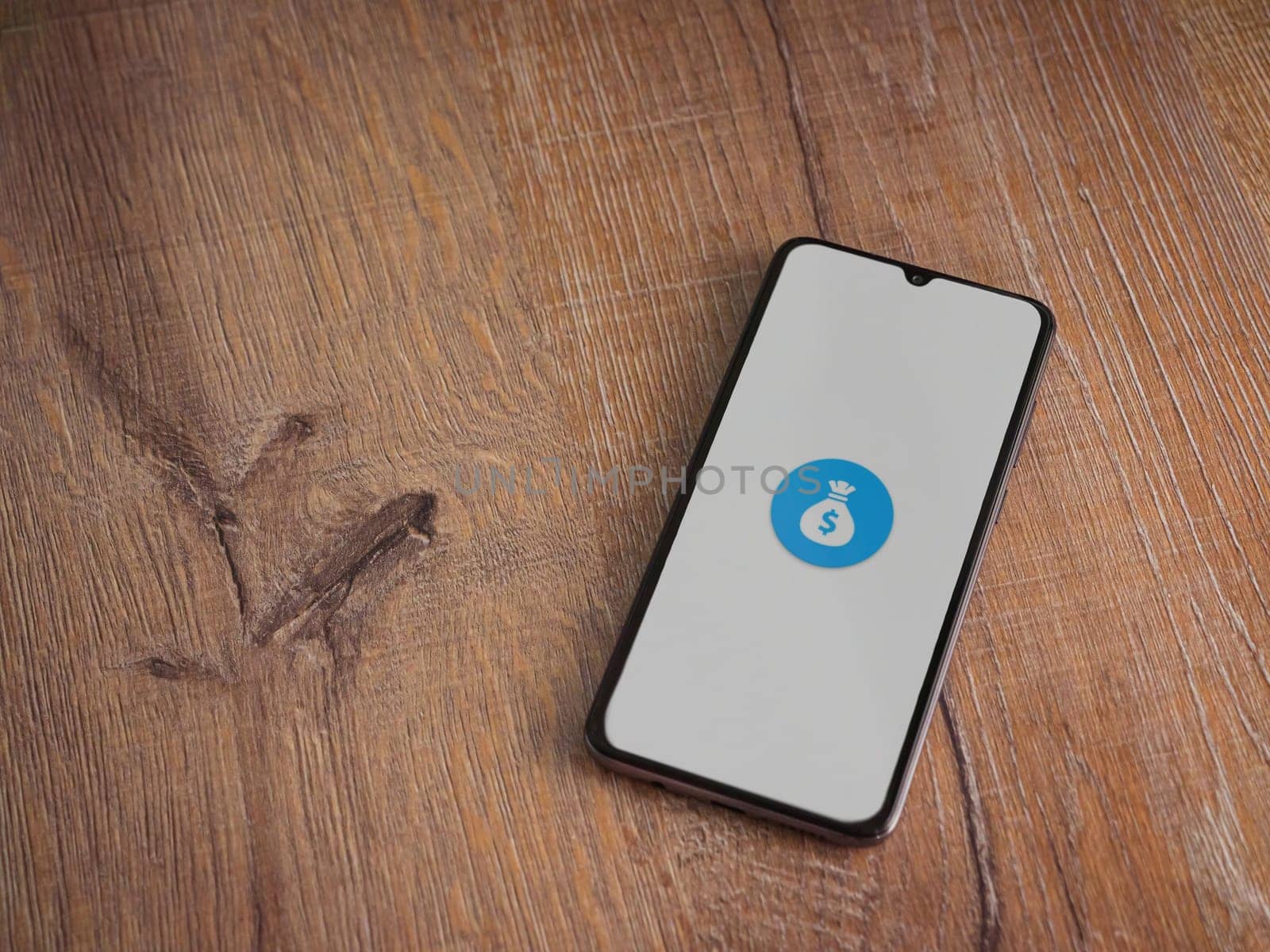 Lod, Israel - July 16,2023: Spender app launch screen on smartphone on wooden background. Top view flat lay with copy space.