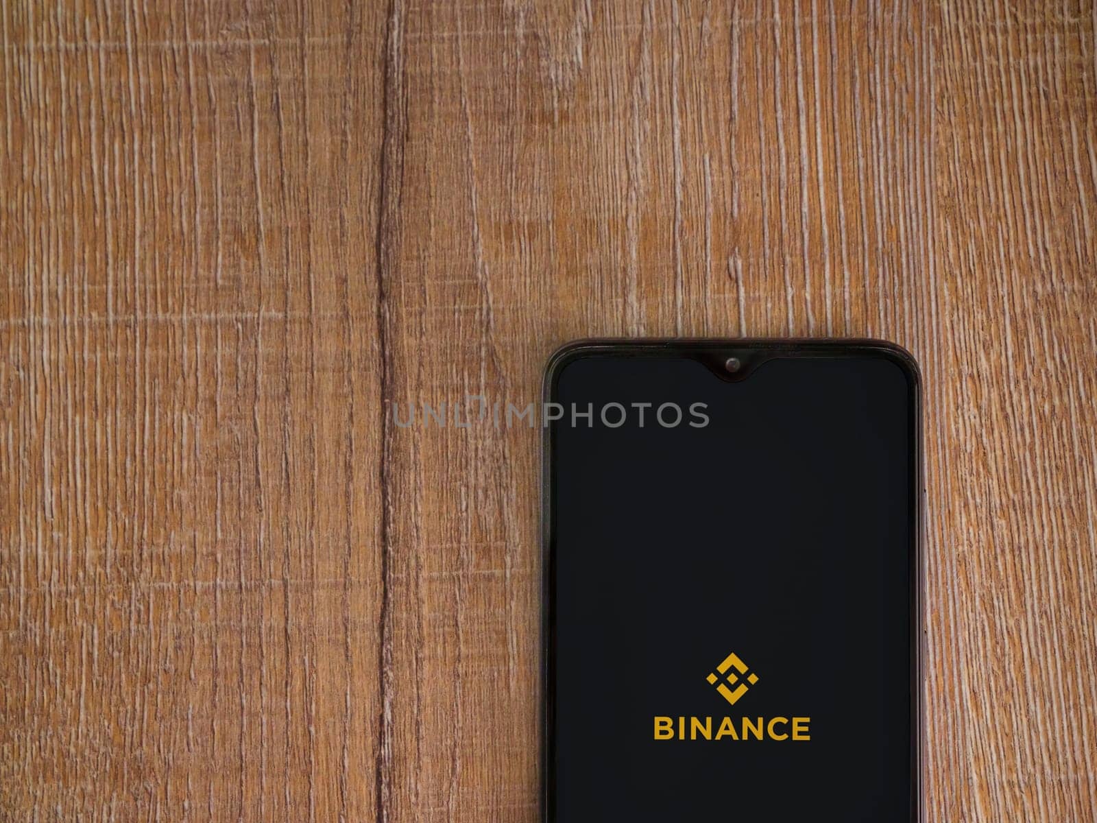 Lod, Israel - July 16,2023: Binance app launch screen on smartphone on wooden background. Top view flat lay with copy space.