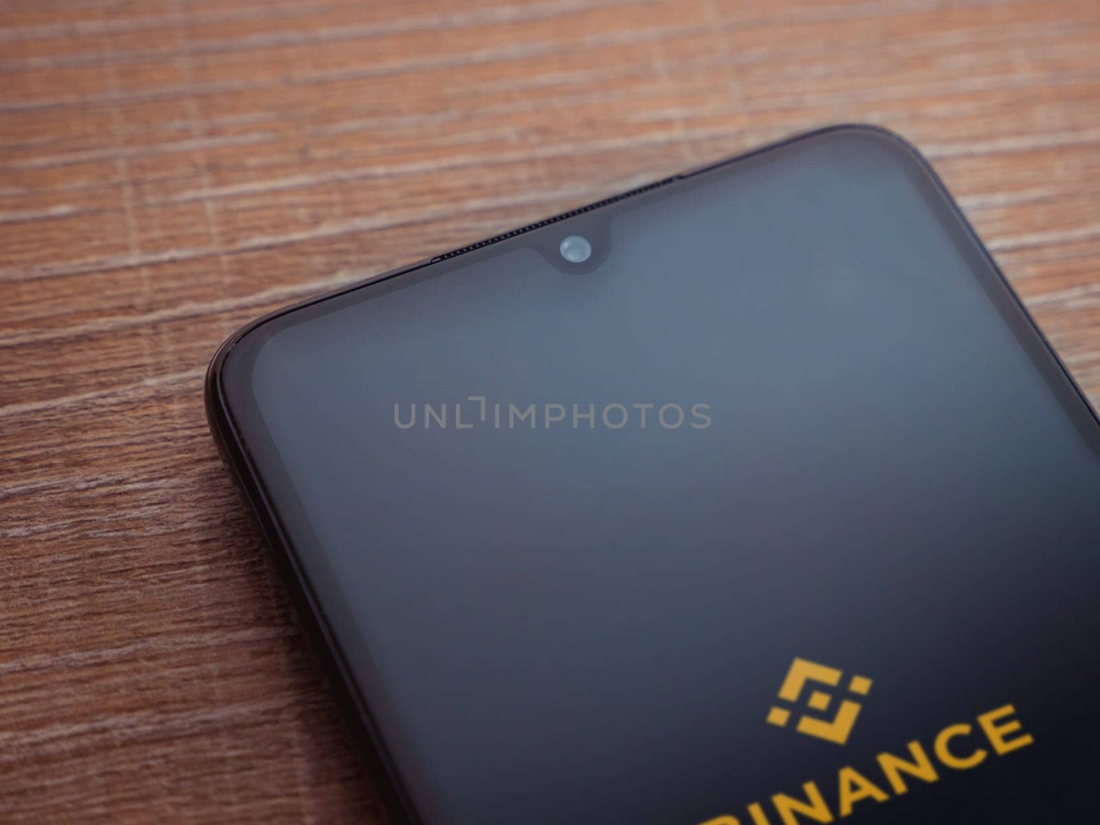 Lod, Israel - July 16,2023: Binance app launch screen on smartphone on wooden background. Top view flat lay with copy space.