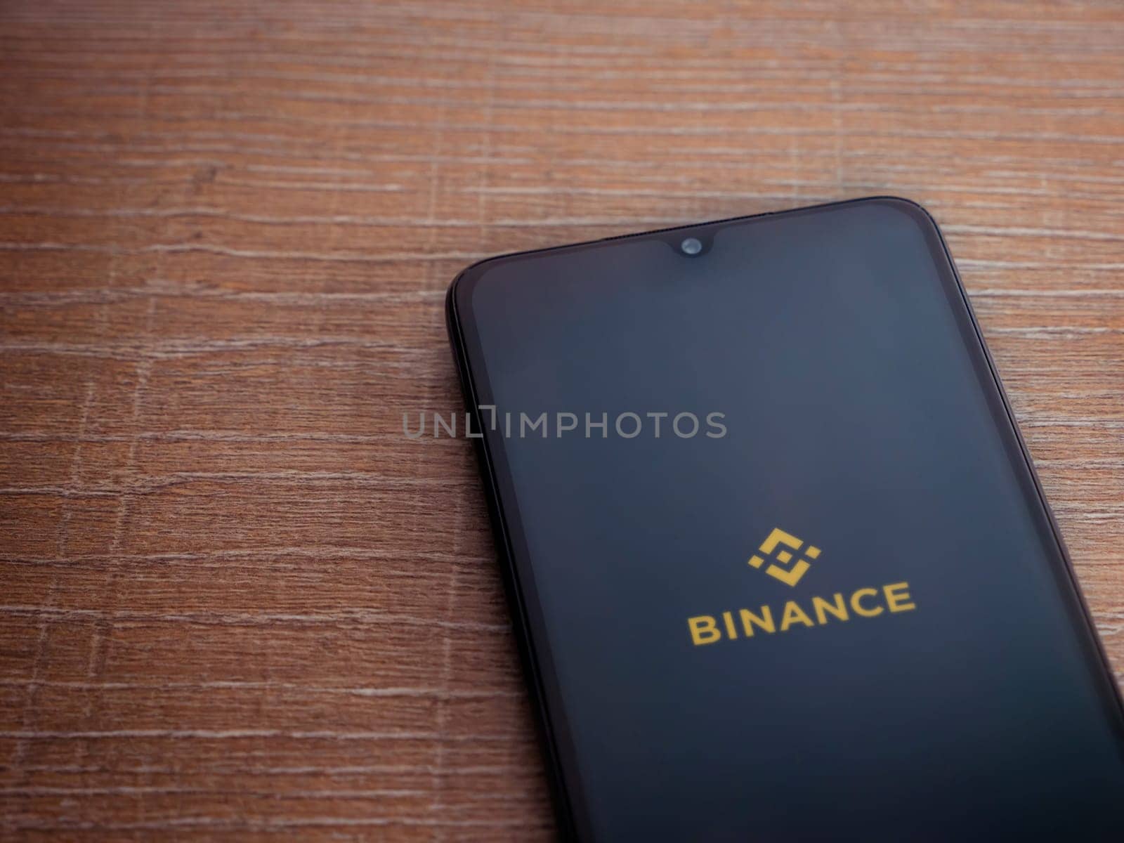 Lod, Israel - July 16,2023: Binance app launch screen on smartphone on wooden background. Top view flat lay with copy space.