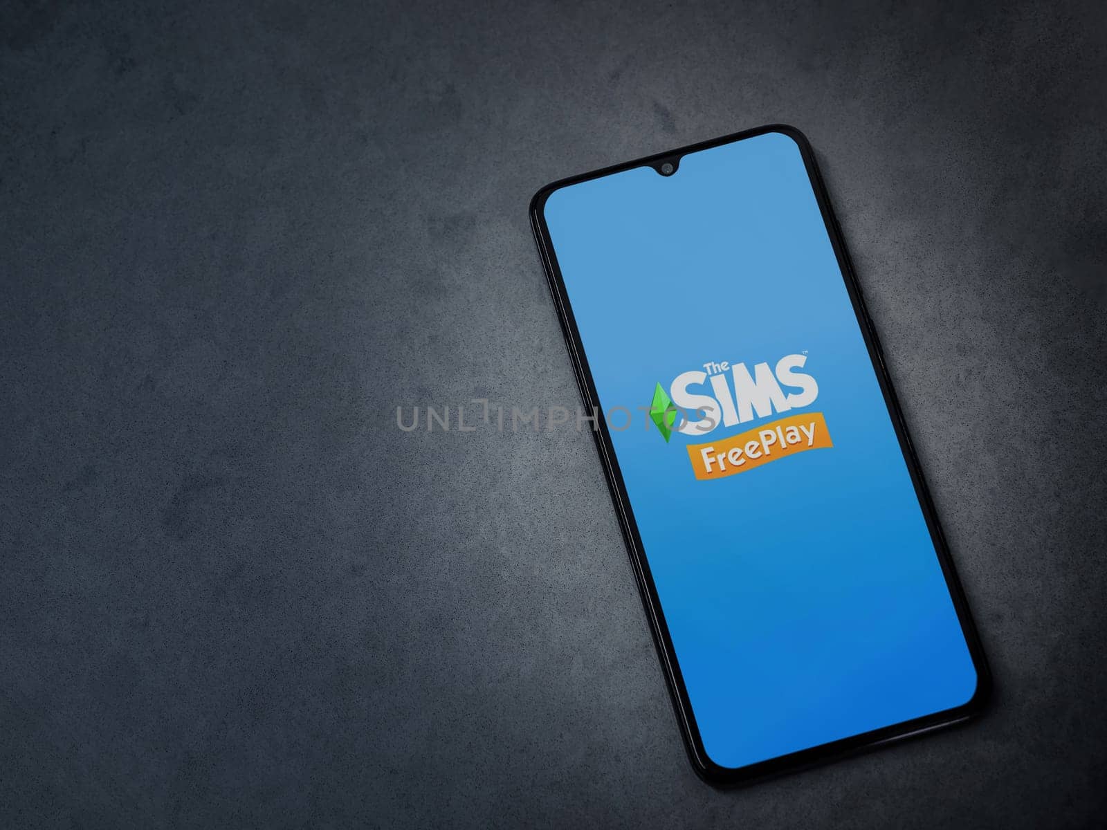 Lod, Israel - July 16,2023: The Sims FreePlay app launch screen on smartphone on dark marble stone background. Top view flat lay with copy space.