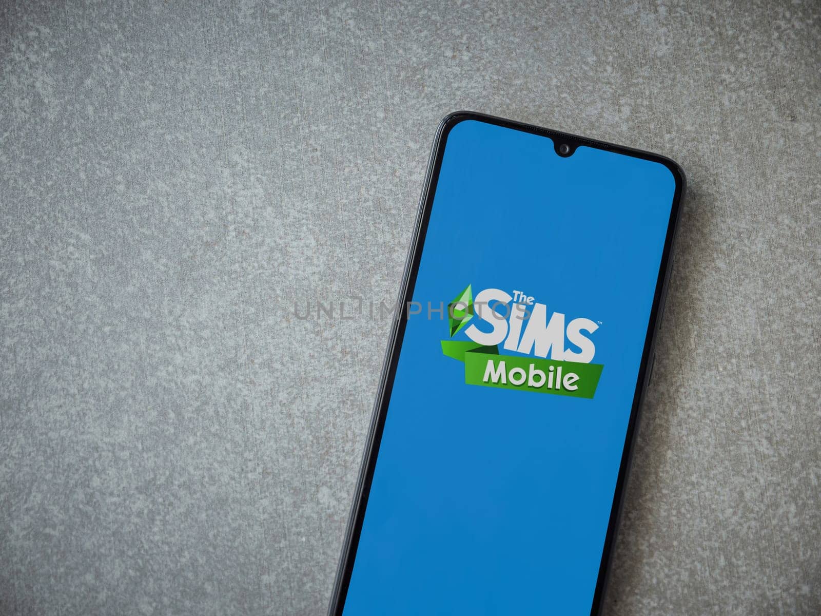 Lod, Israel - July 16,2023: The Sims Mobile app launch screen on smartphone on ceramic stone background. Top view flat lay with copy space.