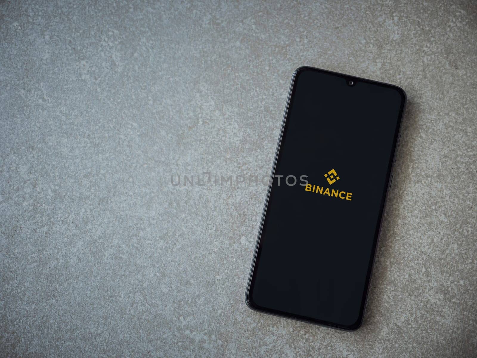 Lod, Israel - July 16,2023: Binance app launch screen on smartphone on ceramic stone background. Top view flat lay with copy space.