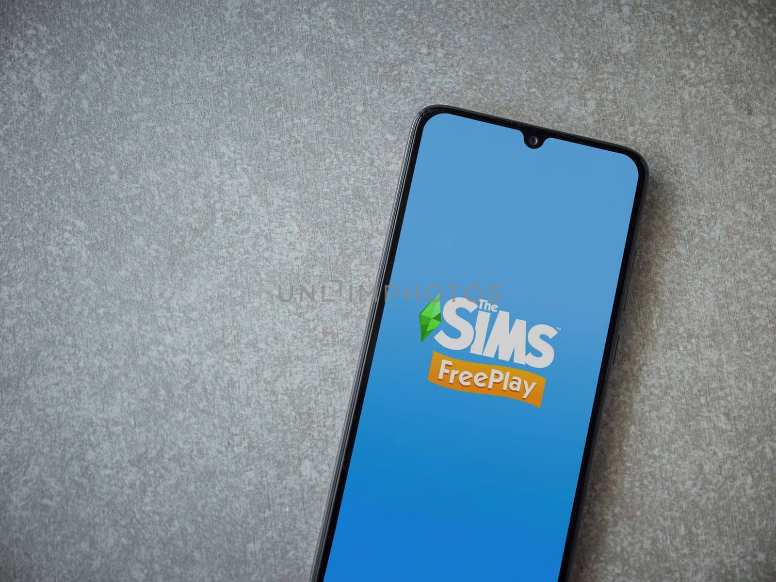 Lod, Israel - July 16,2023: The Sims FreePlay app launch screen on smartphone on ceramic stone background. Top view flat lay with copy space.