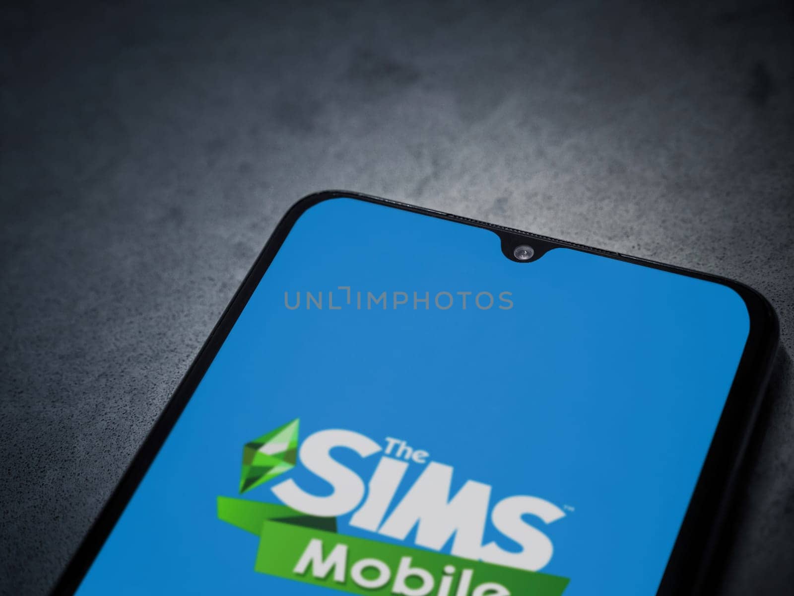 Lod, Israel - July 16,2023: The Sims Mobile app launch screen on smartphone on dark marble stone background. Top view flat lay with copy space.