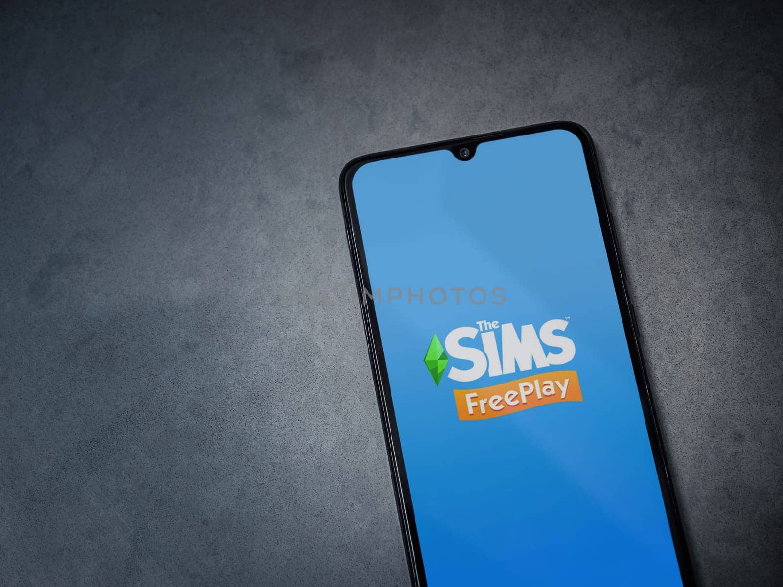 Lod, Israel - July 16,2023: The Sims FreePlay app launch screen on smartphone on dark marble stone background. Top view flat lay with copy space.