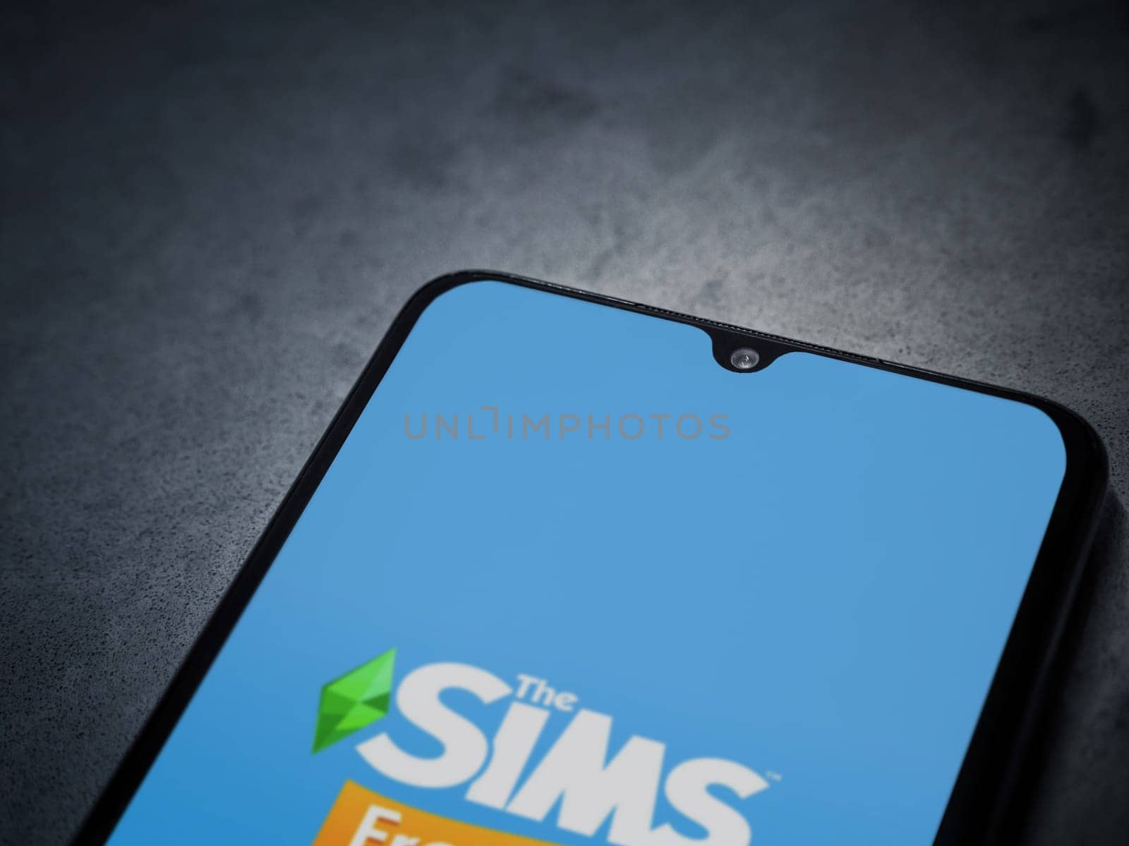 Lod, Israel - July 16,2023: The Sims FreePlay app launch screen on smartphone on dark marble stone background. Top view flat lay with copy space.