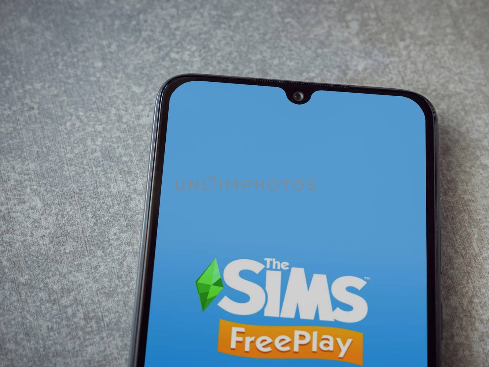 Lod, Israel - July 16,2023: The Sims FreePlay app launch screen on smartphone on ceramic stone background. Top view flat lay with copy space.