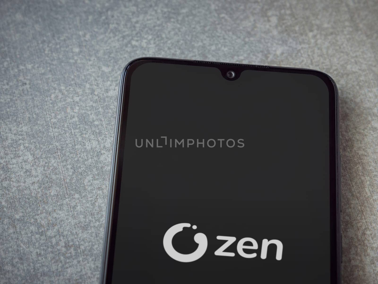 Lod, Israel - July 16,2023: ZEN.COM app launch screen on smartphone on ceramic stone background. Top view flat lay with copy space.