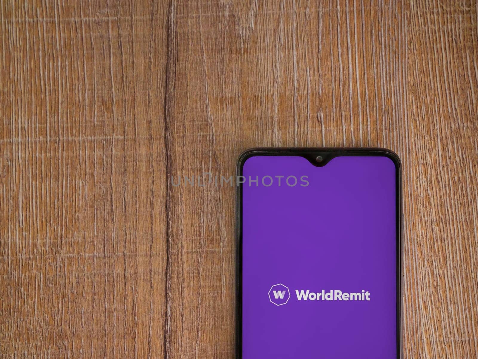 Lod, Israel - July 16,2023: WorldRemit app launch screen on smartphone on wooden background. Top view flat lay with copy space.