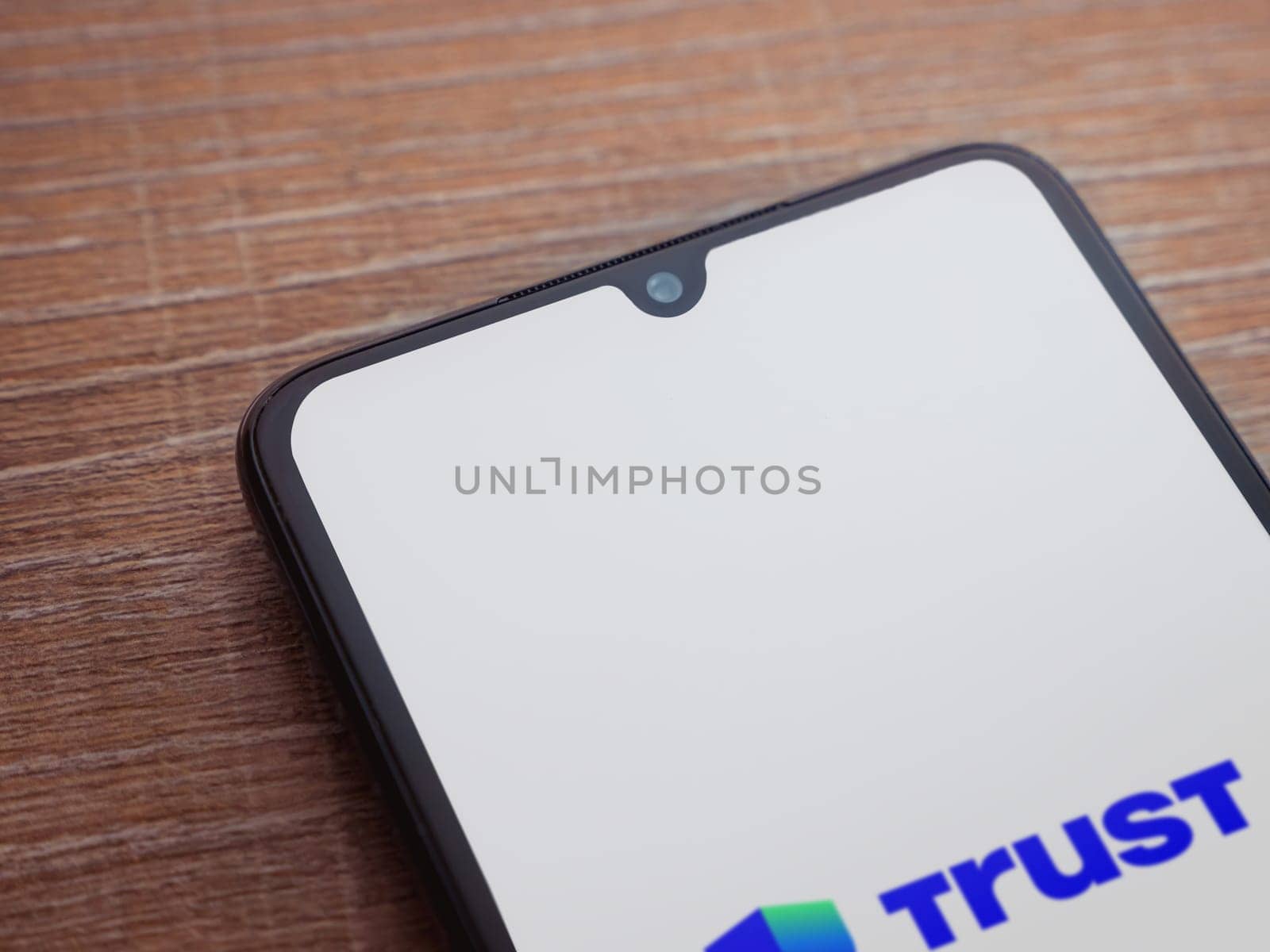 Lod, Israel - July 16,2023: Trust Wallet app launch screen on smartphone on wooden background. Top view flat lay with copy space.