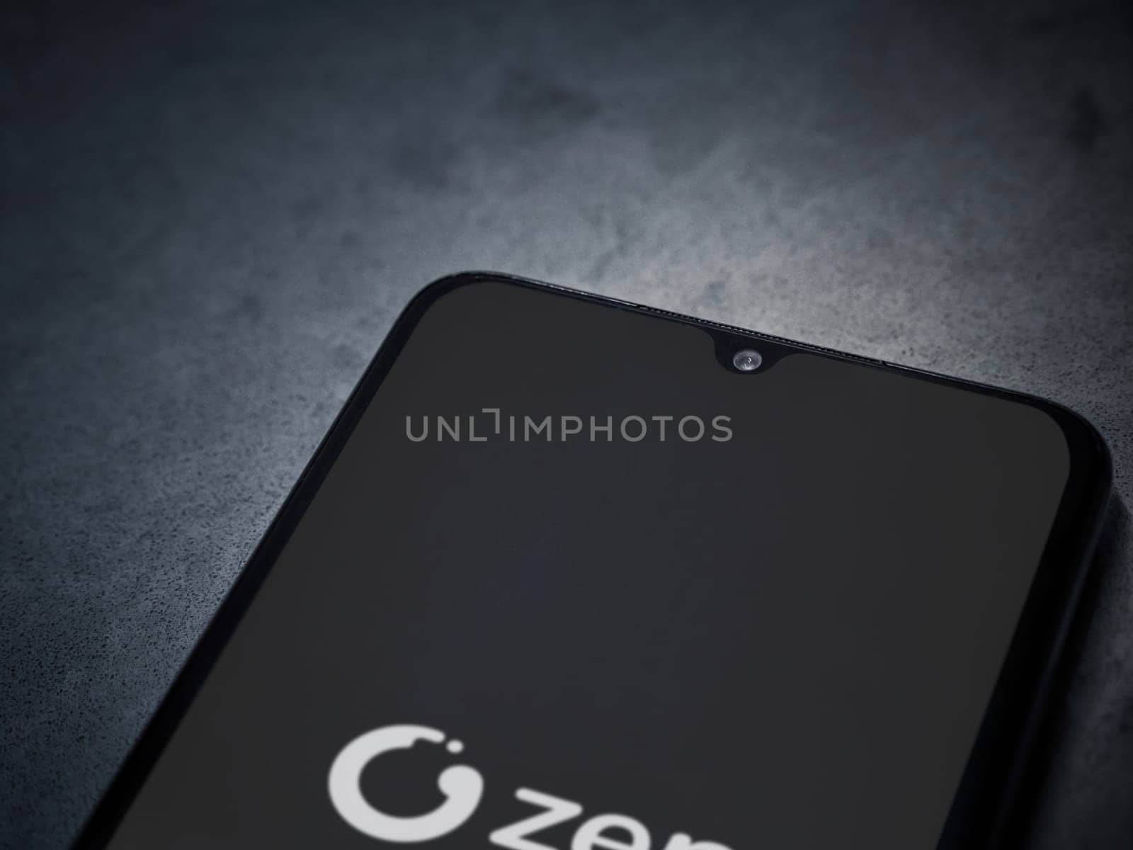 Lod, Israel - July 16,2023: ZEN.COM app launch screen on smartphone on dark marble stone background. Top view flat lay with copy space.