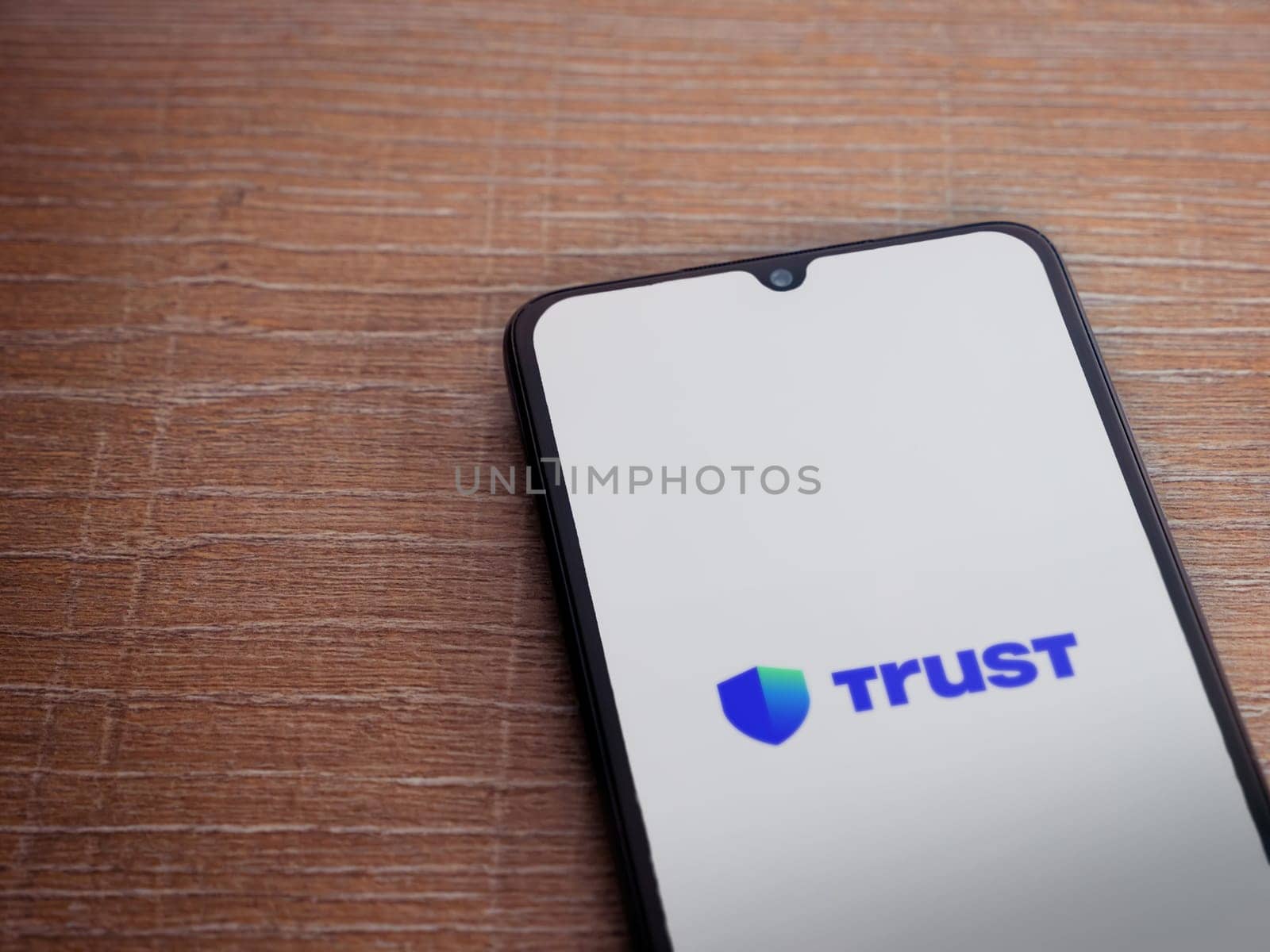 Lod, Israel - July 16,2023: Trust Wallet app launch screen on smartphone on wooden background. Top view flat lay with copy space.