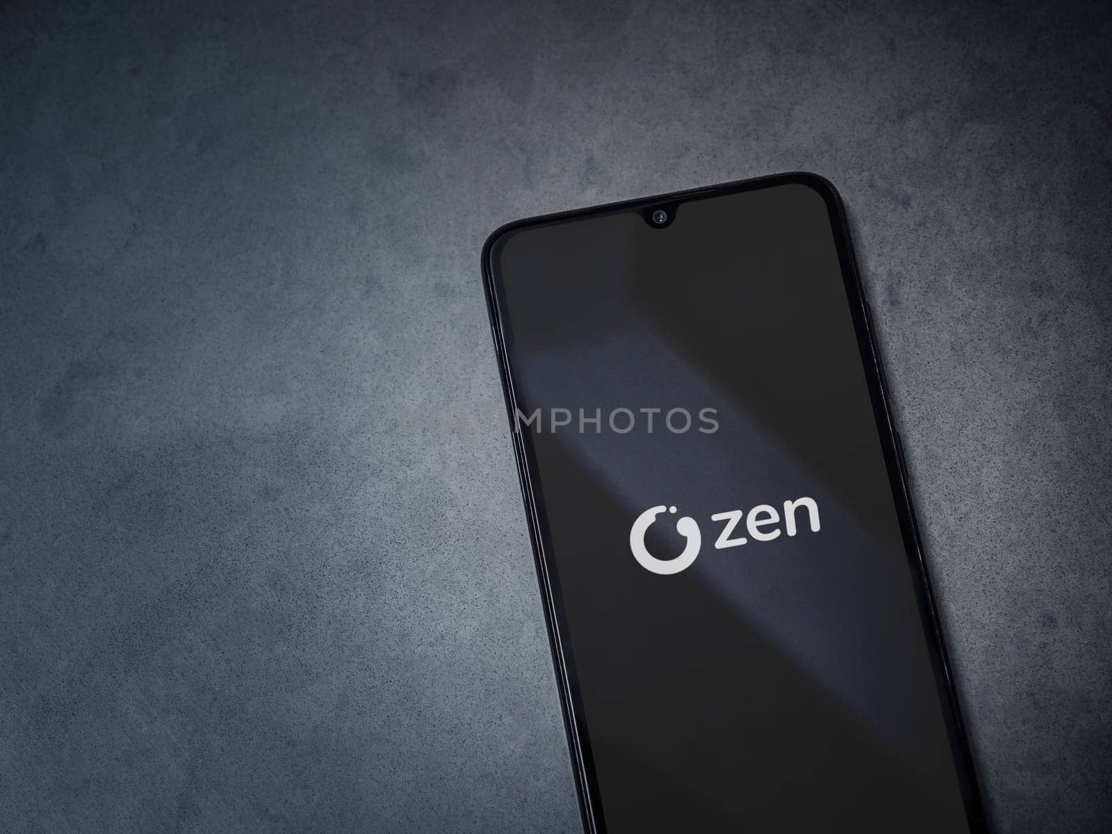 Lod, Israel - July 16,2023: ZEN.COM app launch screen on smartphone on dark marble stone background. Top view flat lay with copy space.