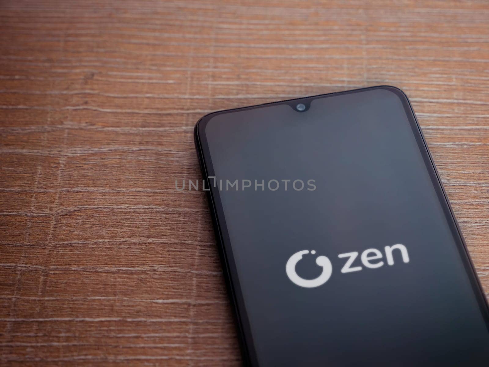 Lod, Israel - July 16,2023: ZEN.COM app launch screen on smartphone on wooden background. Top view flat lay with copy space.