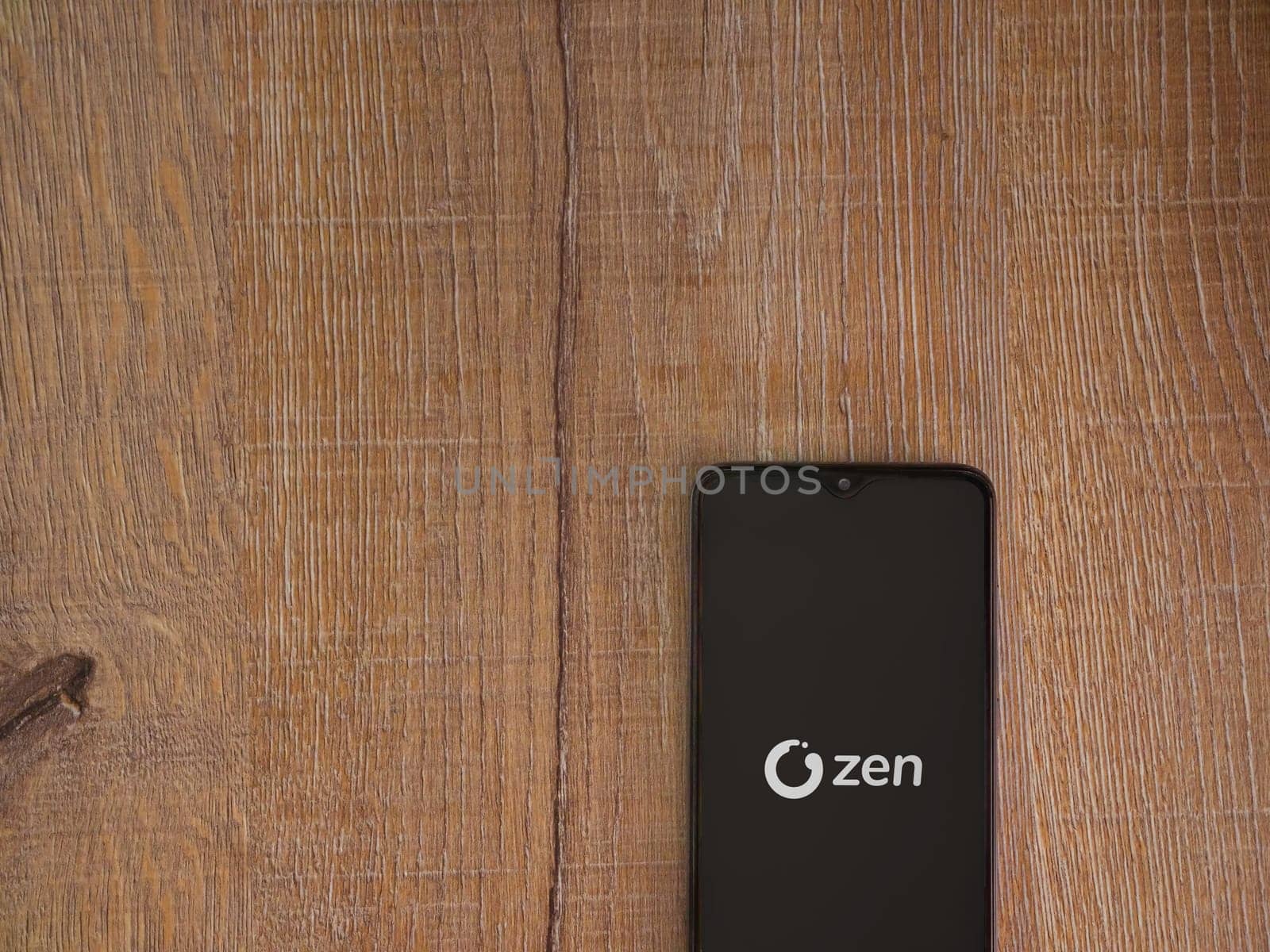 Lod, Israel - July 16,2023: ZEN.COM app launch screen on smartphone on wooden background. Top view flat lay with copy space.