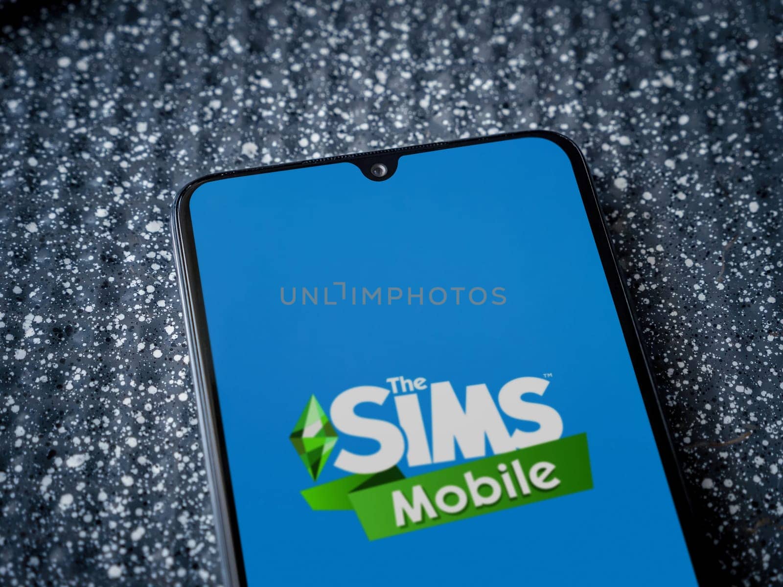 Lod, Israel - July 16,2023: The Sims Mobile app launch screen on smartphone on metallic background. Close up top view flat lay.
