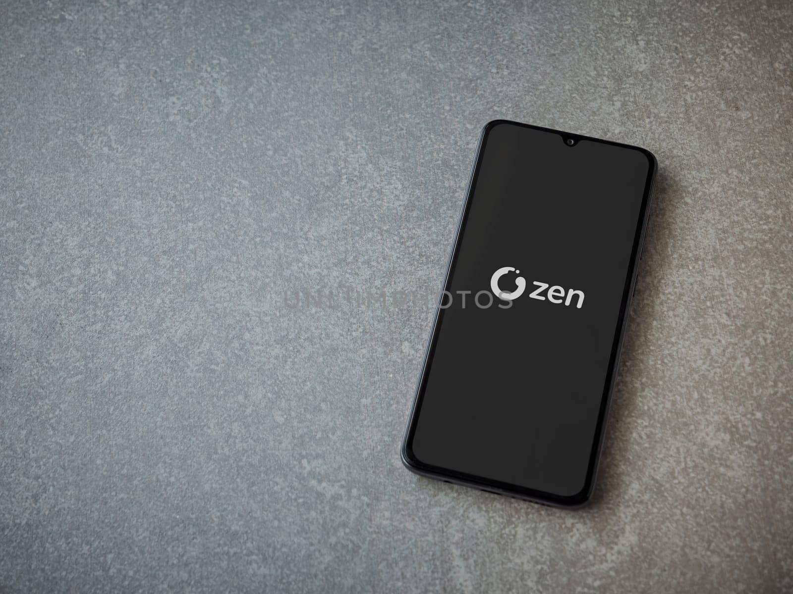 Lod, Israel - July 16,2023: ZEN.COM app launch screen on smartphone on ceramic stone background. Top view flat lay with copy space.