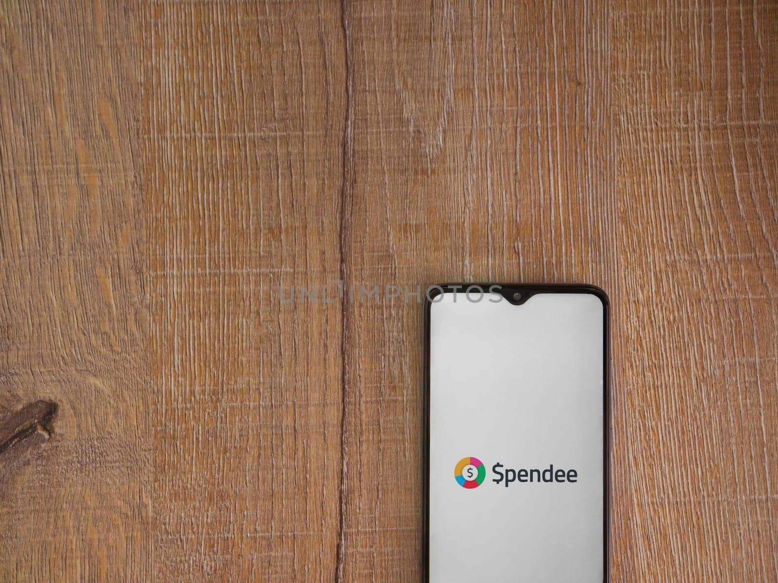 Lod, Israel - July 16,2023: Spendee app launch screen on smartphone on wooden background. Top view flat lay with copy space.